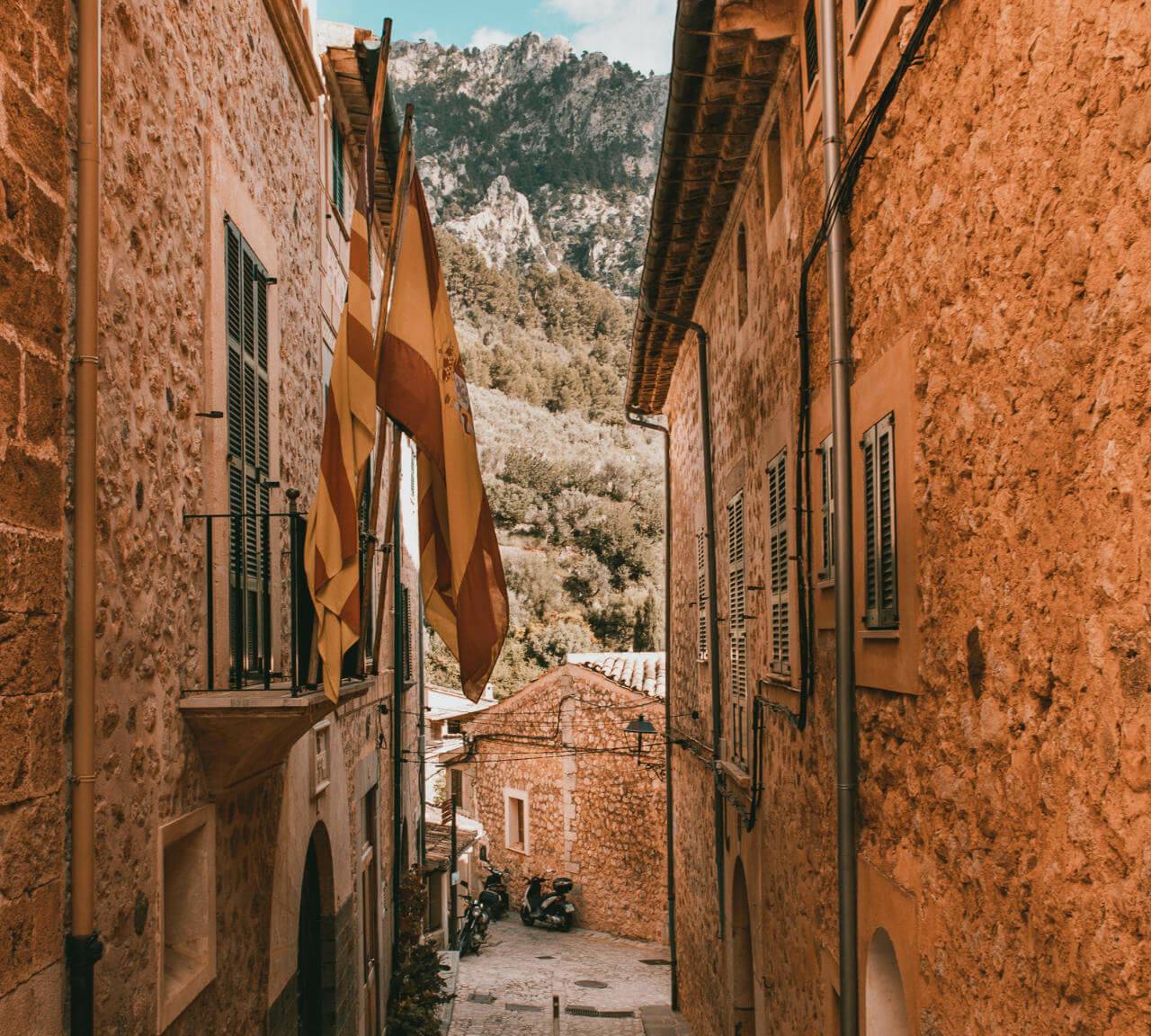 Blick durch eine kleine Gasse in Mallorcas ruhigem Ort Fornalutx auf die Berge der Tramuntana.