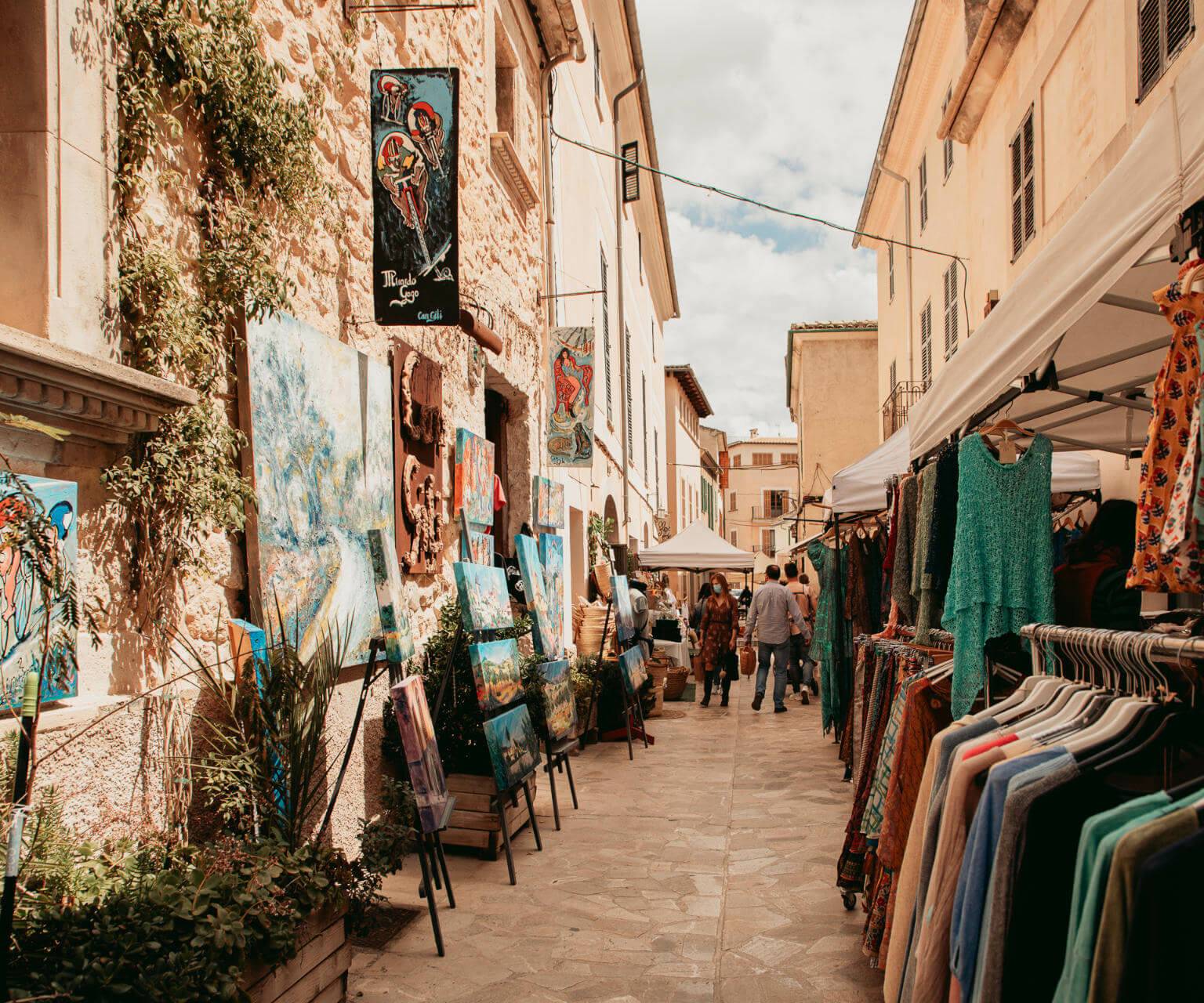 Gemälde und Kleidung ausgestellt für den Verkauf auf dem Wochenmarkt im Dorf Sineu auf Mallorca.