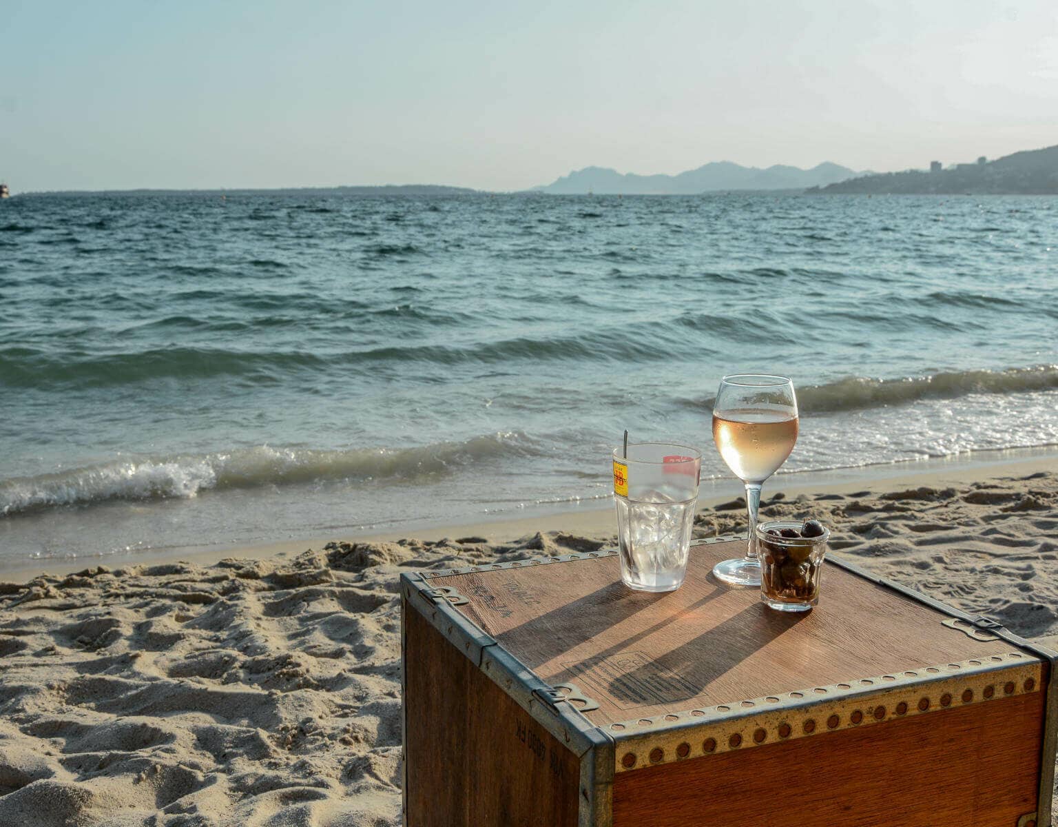 Kiste mit Vino am Strand vor Meereskulisse.