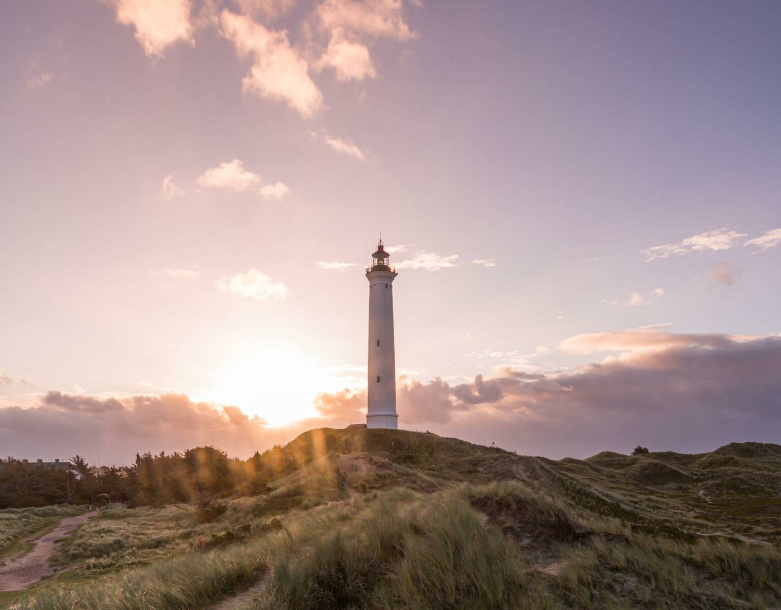 Eine wunderschöne Sehenswürdigkeit in Dänemarks Natur: Der Leuchtturm Lyngvig Fyr, besonders vor dem lila Himmel bei Sonnenuntergang.