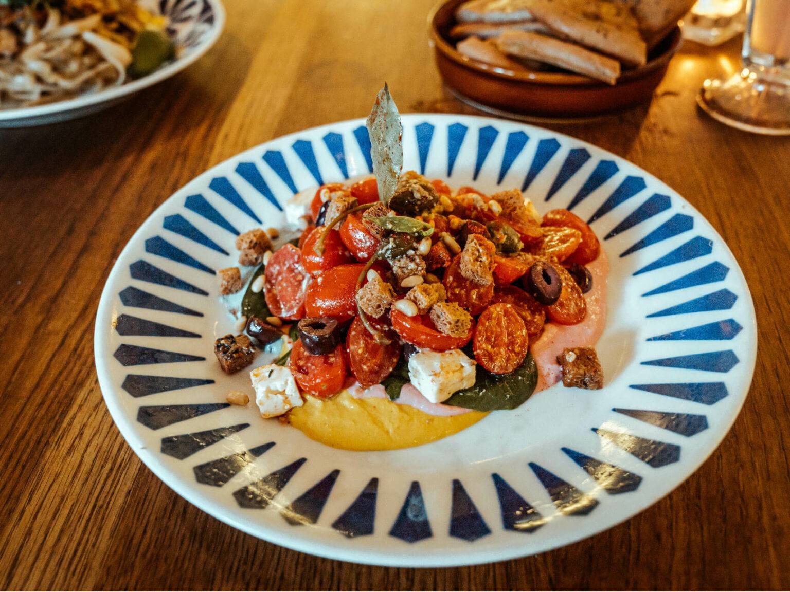 Der Salads for the Gods von Flax & Kale in Barcelona mit mit Spinat, Cherrytomaten, Kalamata Oliven, Kapern und Nüssen auf regenbogenfarbenem Hummus ist nicht nur wunderschön, sondern auch gesund und köstlich.