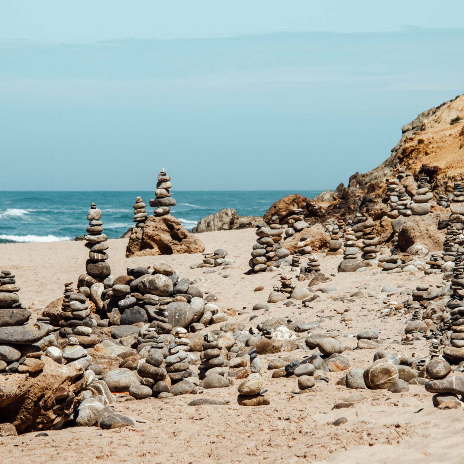 Mehrere Steintürme am Strand nahe des Meeres von Alentejo