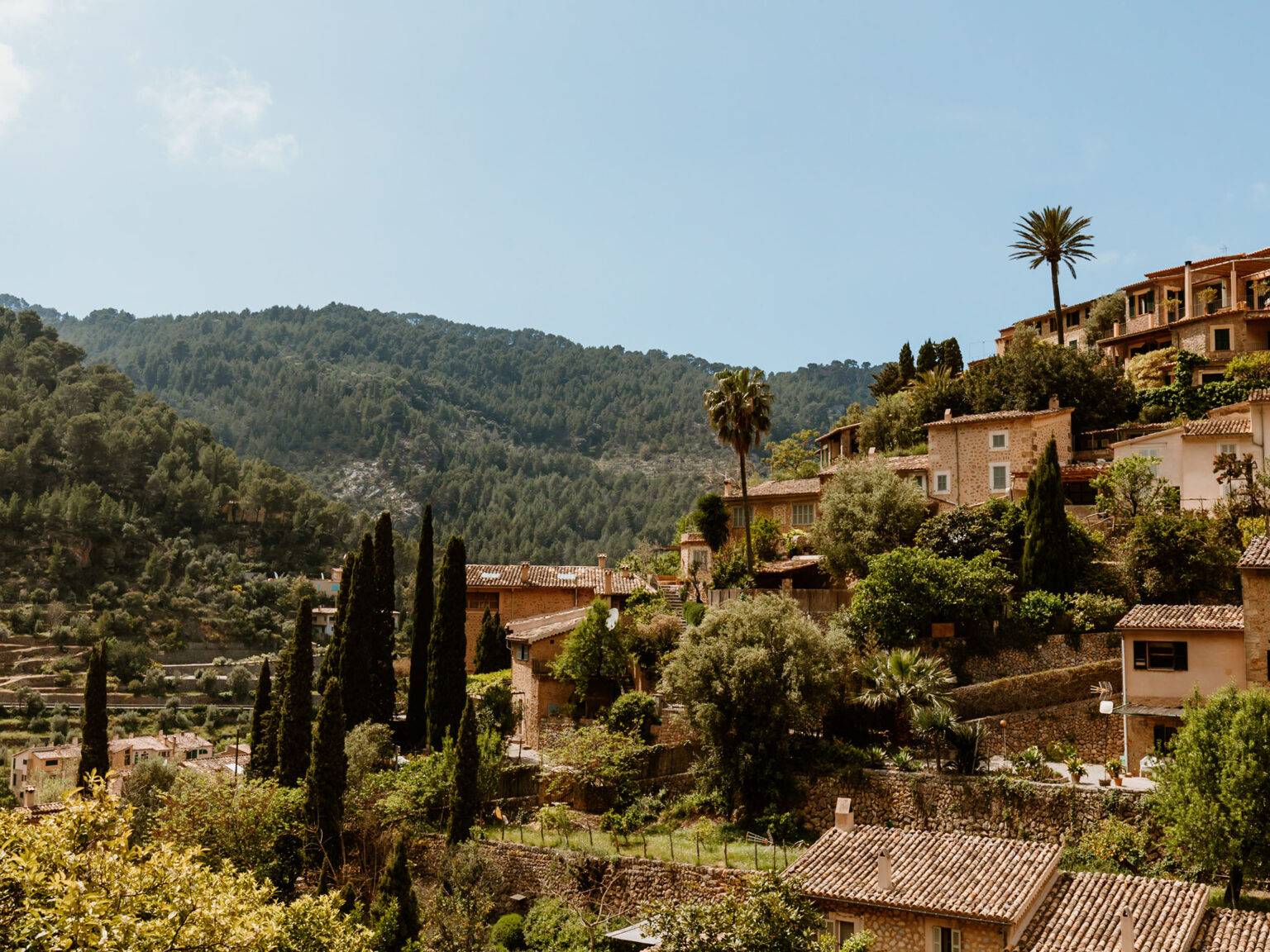 Mallorquinische Steinhäuser in Serra Tramuntana umgeben von einer grünen Berglandschaft.