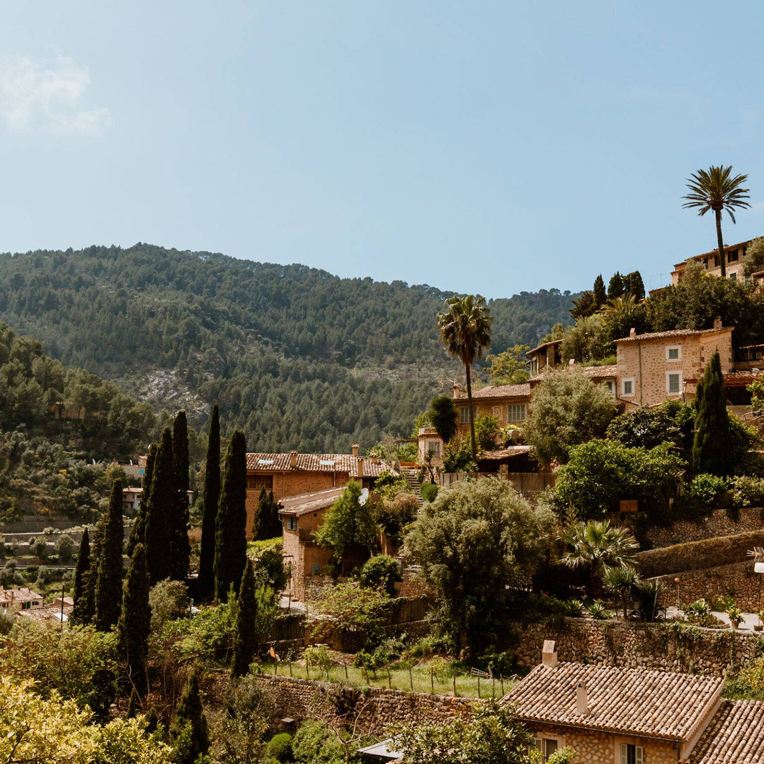Mallorquinische Steinhäuser in Serra Tramuntana umgeben von einer grünen Berglandschaft.