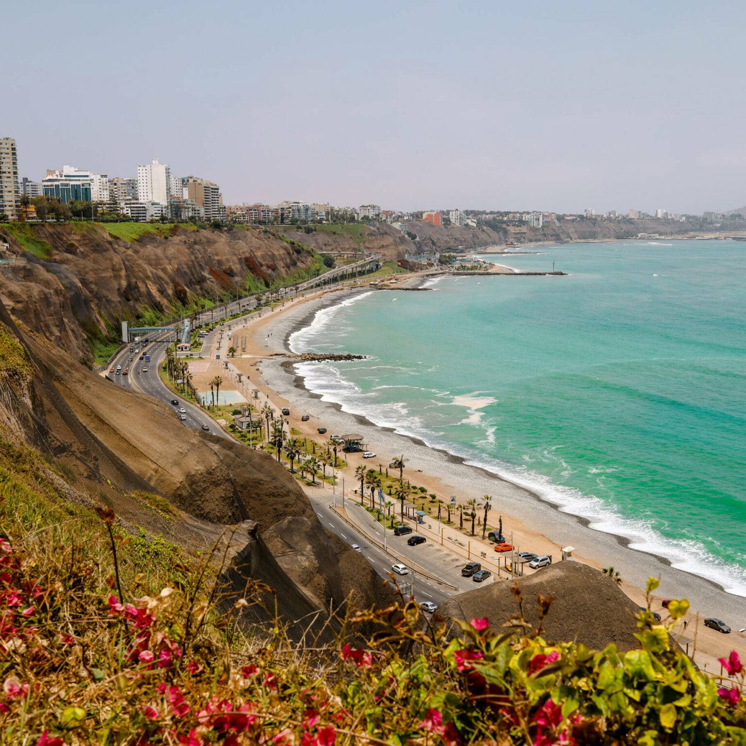 Der Ausblick auf Limas Küste mit grünen Hügeln und türkisblauem Meer.