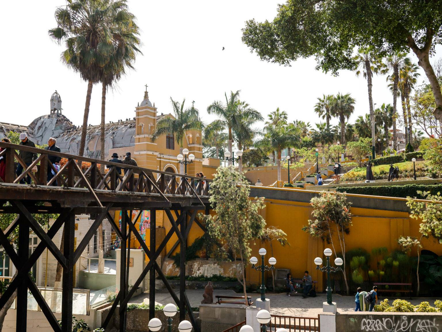 Zwischen Palmen ist die, aus dunklem Holz bestehende, Seufzerbrücke in Lima.