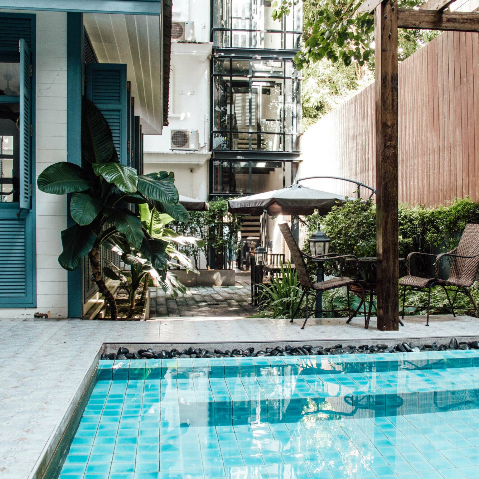 Dschungelartige Pflanzen ragen inmitten eines Hotels mit Pool empor.