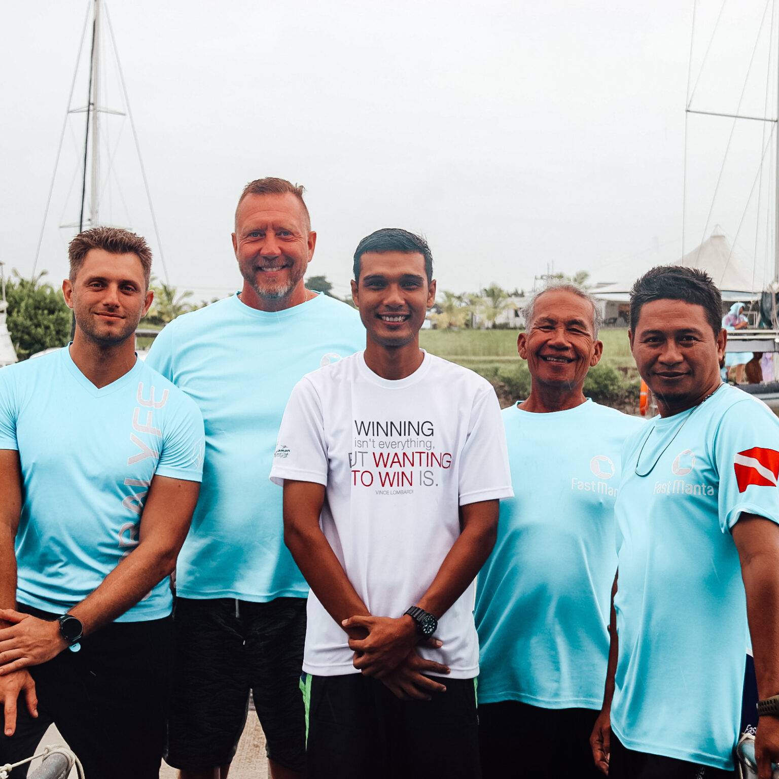 Fünf Männer aus dem Team von Fast Manta in Krabi mit Booten im Hintergrund.