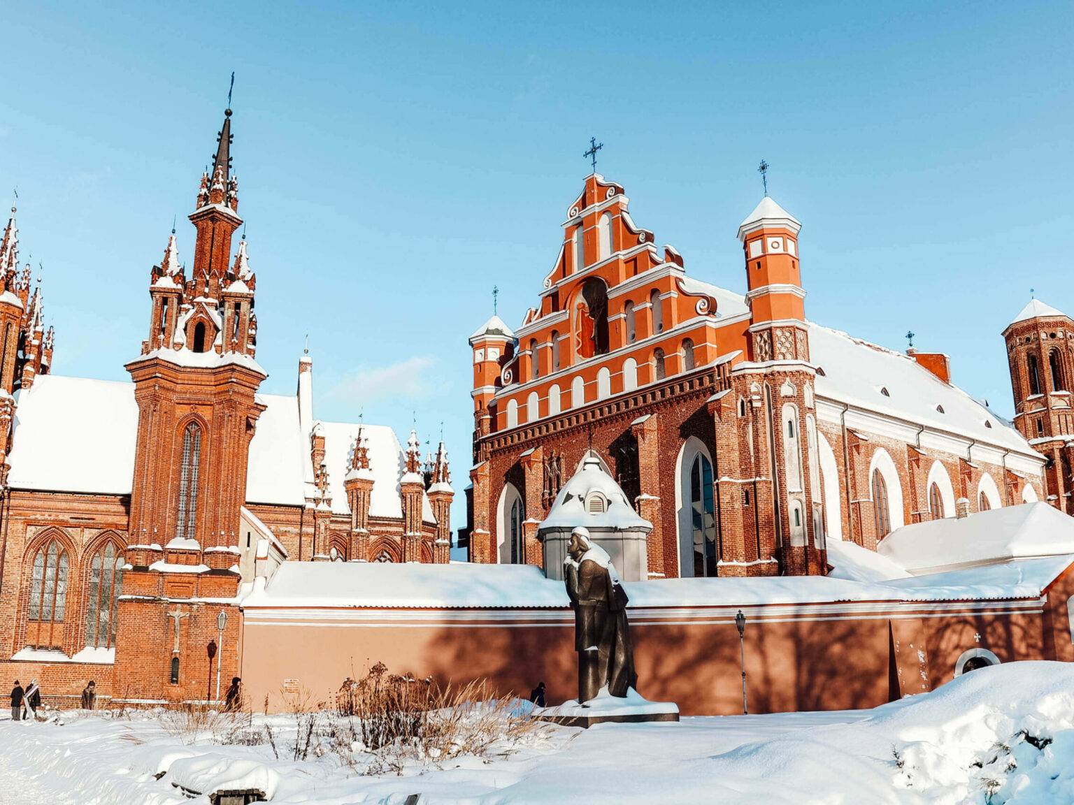 Die backsteinfarbene Kirche St. Anna in Vilnius im Winter mit Schnee bedeckt.