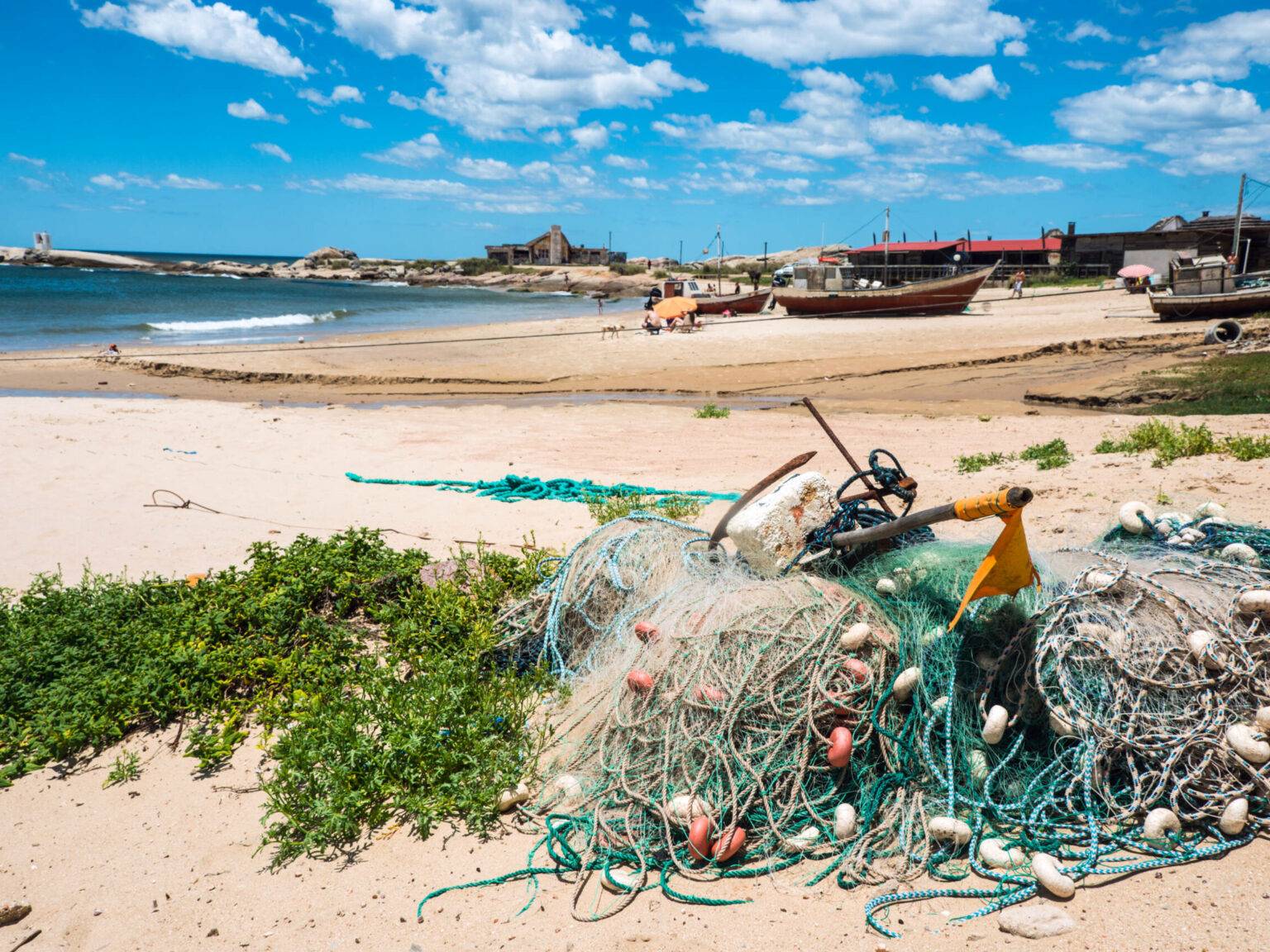 Im Fischerdörfchen Punta del Diablo in Uruguay liegen kleine Boote und Fischernetze am Strand.
