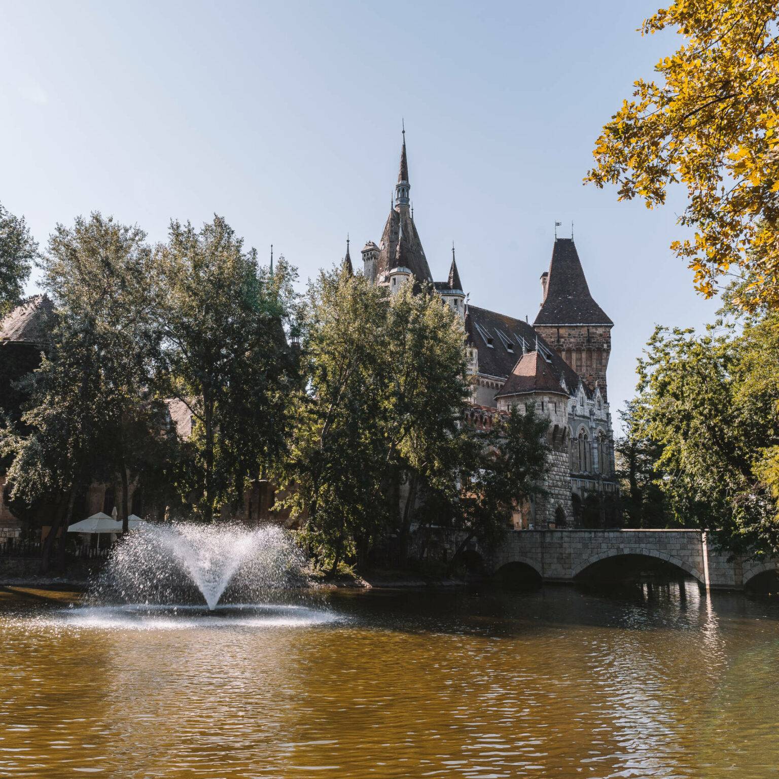 Die alte Burg Vajdahunyad in Budapest versteckt sich hinter einem See und Bäumen.