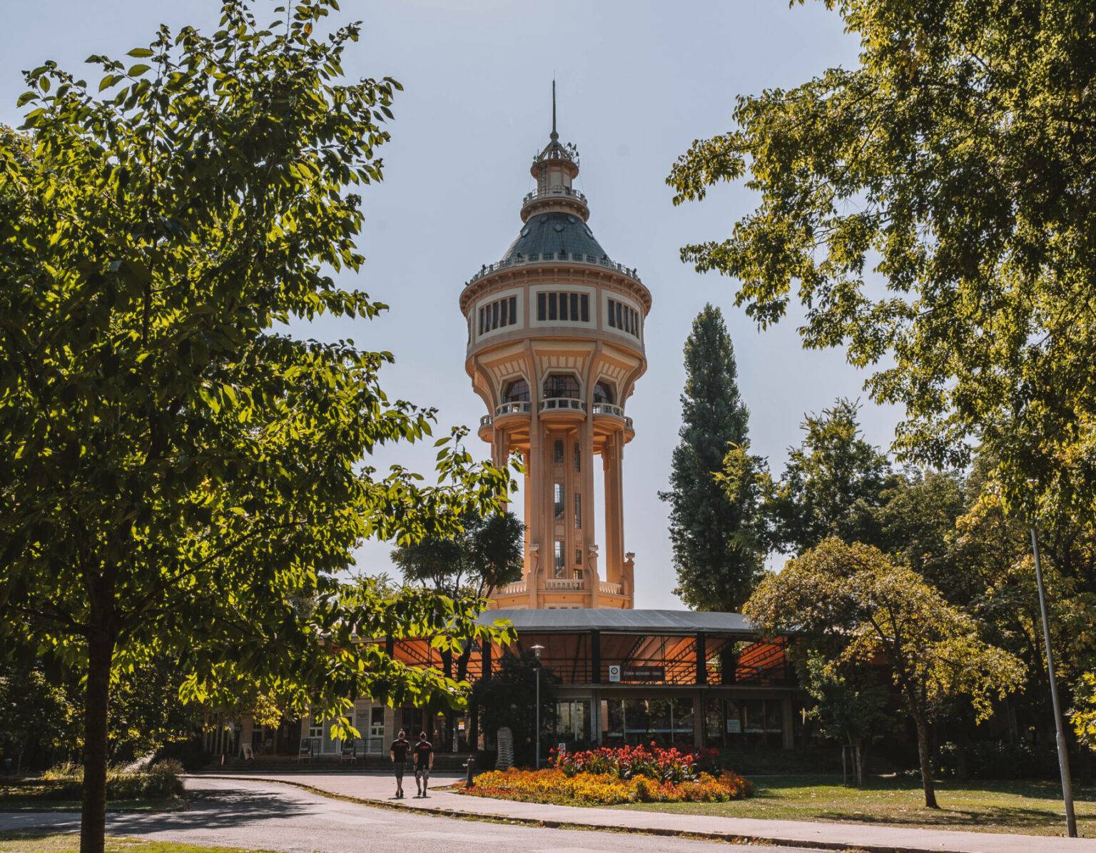 Der Wasserturm auf der Margareteninsel in Budapest umgeben von Bäumen.