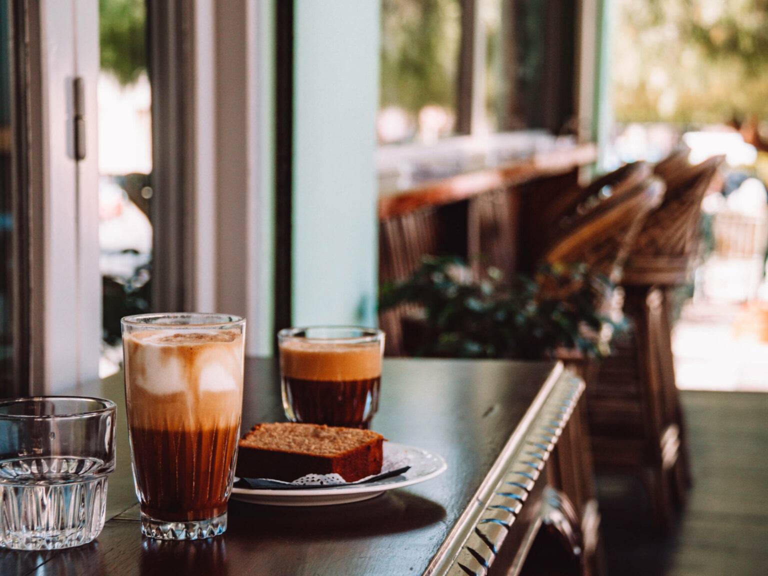 2 Gläser mit Kaffee und ein Stück Kuchen auf dem Tisch in der Café-Bar Ble Papagalos.