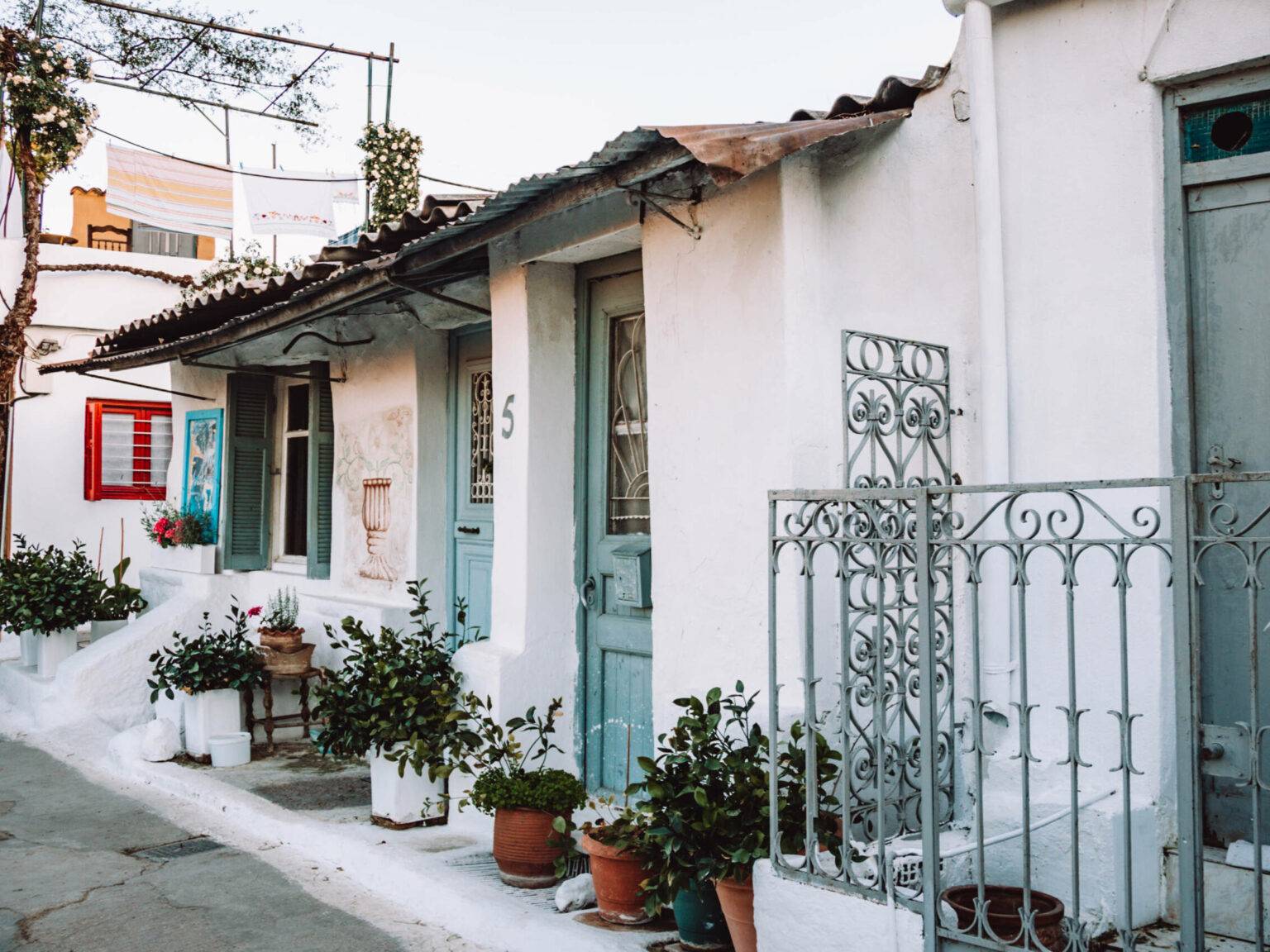 Kleine weiße Häuschen mit bunten Türen und Fensterläden im Viertel Anafiotika in Athen.
