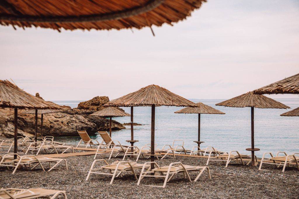 Leere Liegen und Bastschirme am Kakkos Beach auf Kreta.