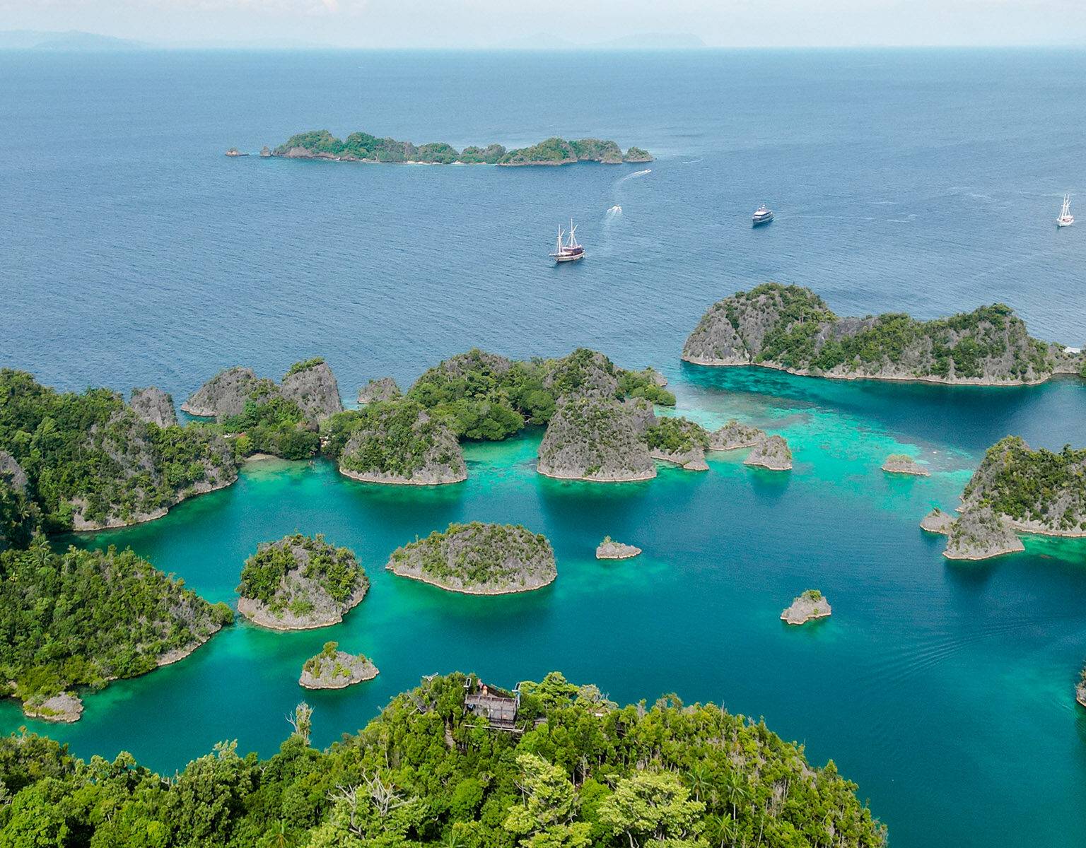 Kleine steinerne Inseln umgeben von türkisblauem Meer bei Piaynemo Island auf Raja Ampat.