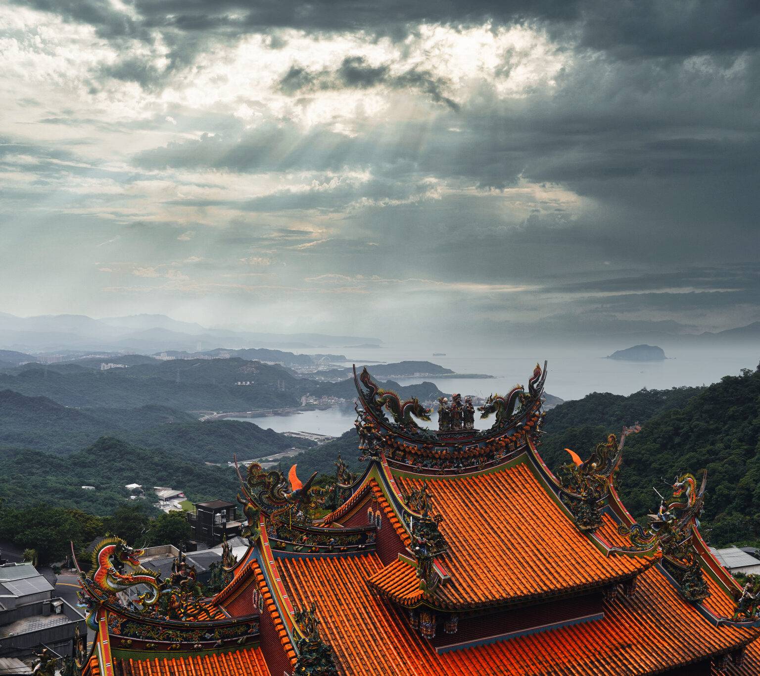 Blick von Jiufen über das rot gedeckte und mit Drachenskulpturen verzierte Tempeldach auf die Nordküste Taiwans.