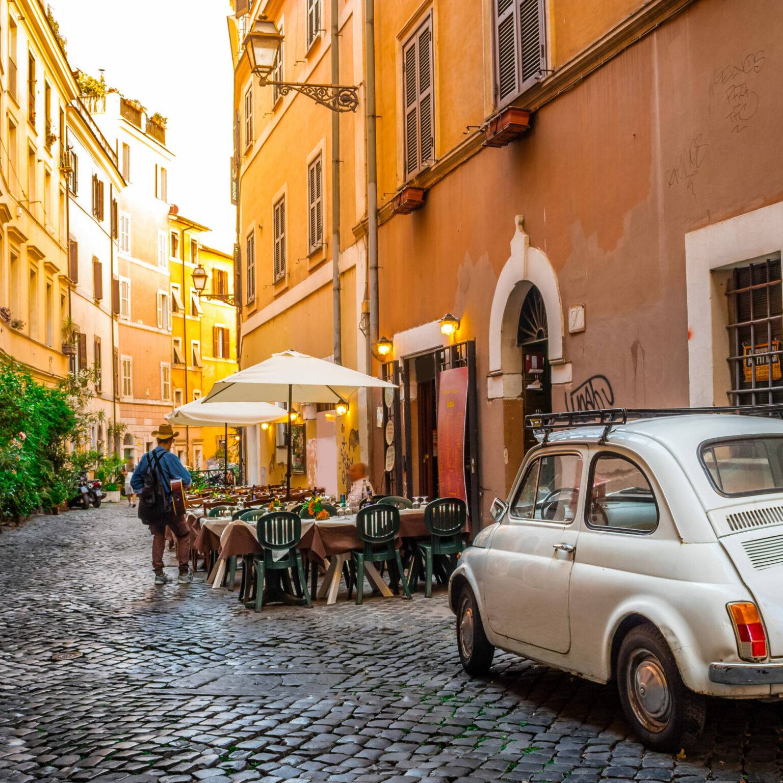 In Roms berühmten Stadtviertel Trastevere parkt ein alter Fiat 500 in einer Gasse.