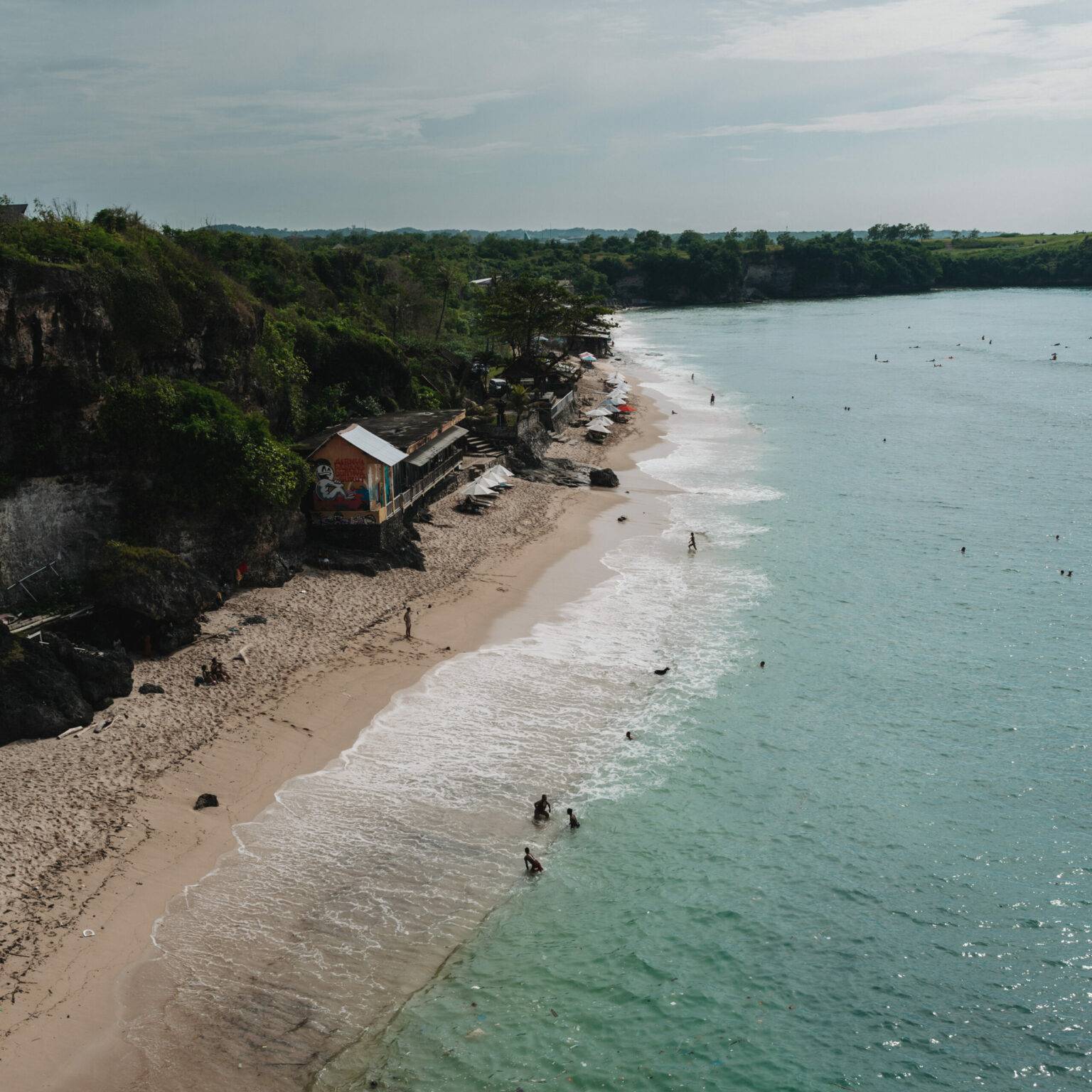 Ein Strandabschnitt mit türkisblauem Wasser und goldgelbem Sand in Bali.
