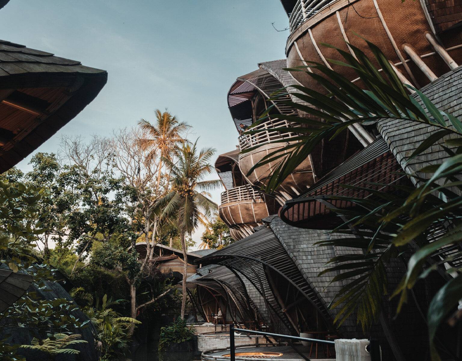 Die Hotelanlage des Ulaman Bali, die aus viele Bungalows besteht. Diese sind zweistöckig und Vogelnestartig gebaut. Im Hintergrund viele Palmen.