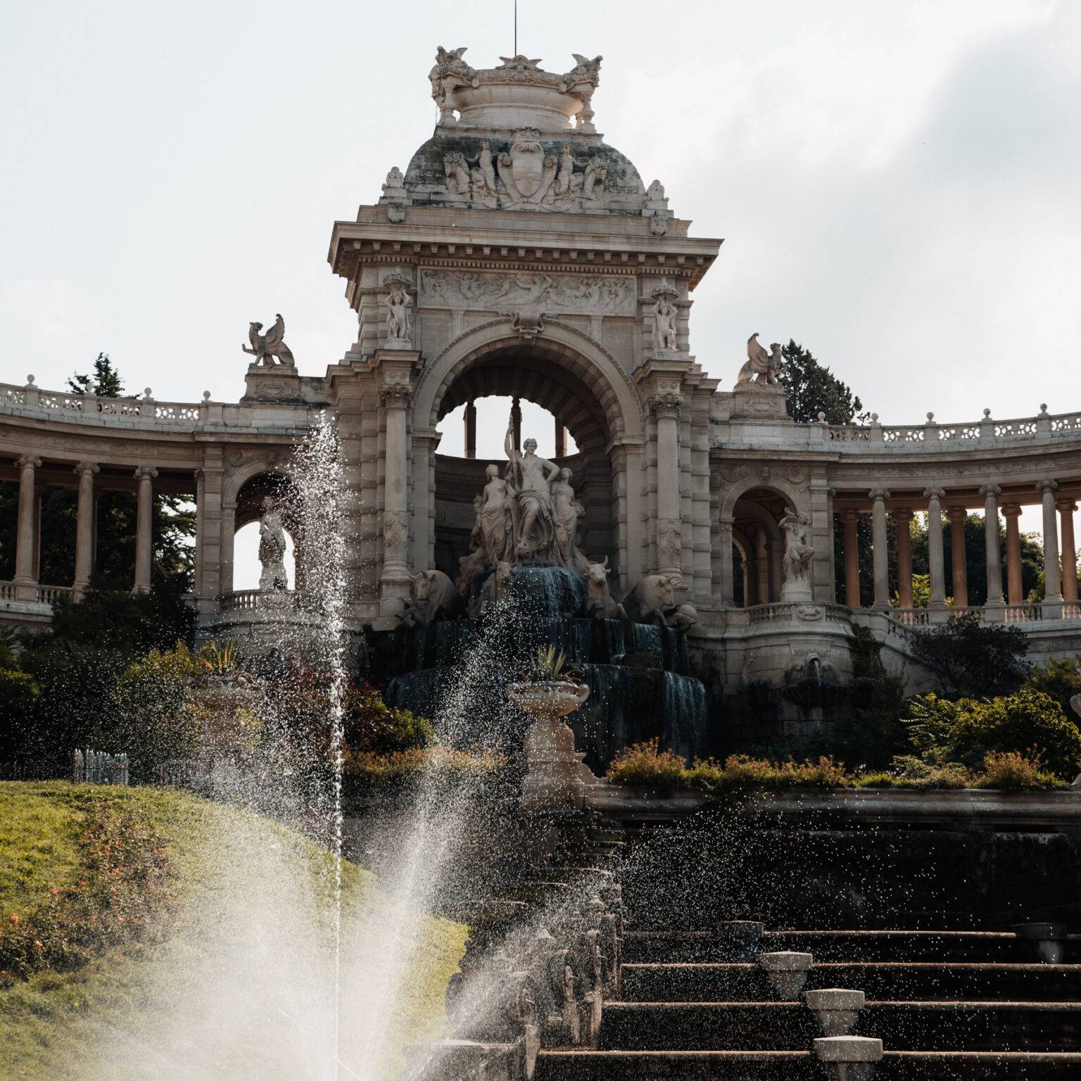 Ein Springbrunnen vor dem Palais Longchamp, umgeben von weißen Statuen und Verziehrungen.