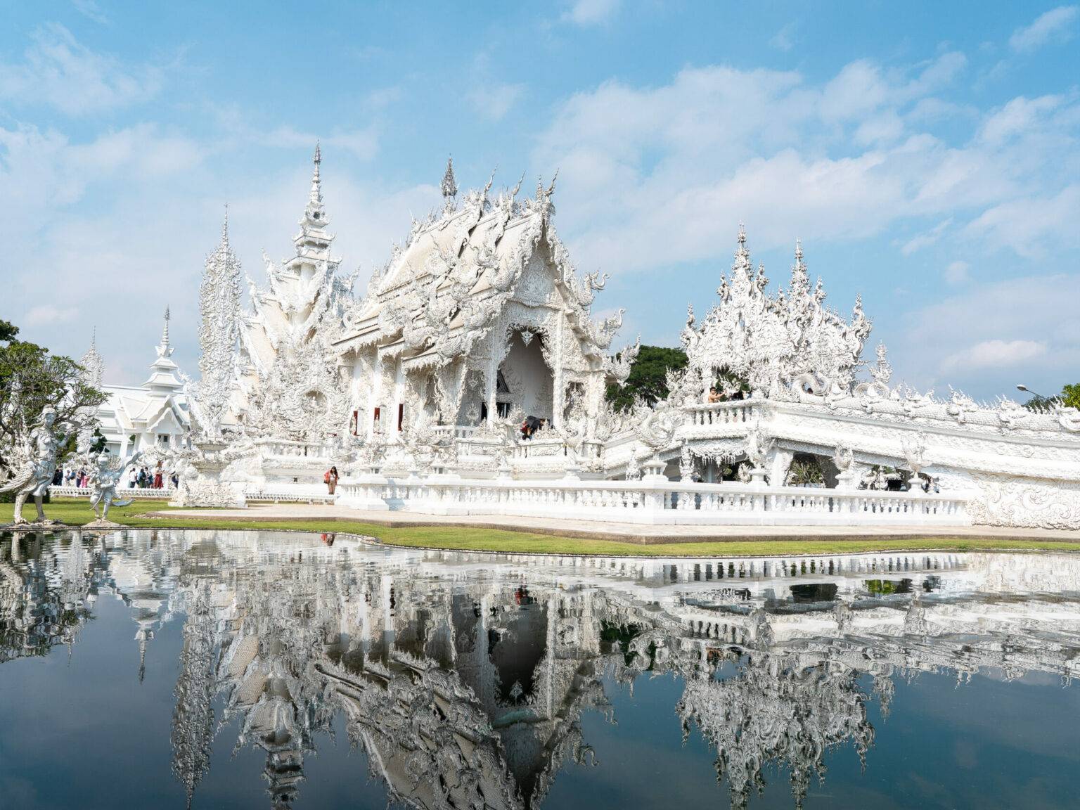 Der weiße Tempel in Chiang Rai spiegelt sich im Wasser des Sees.