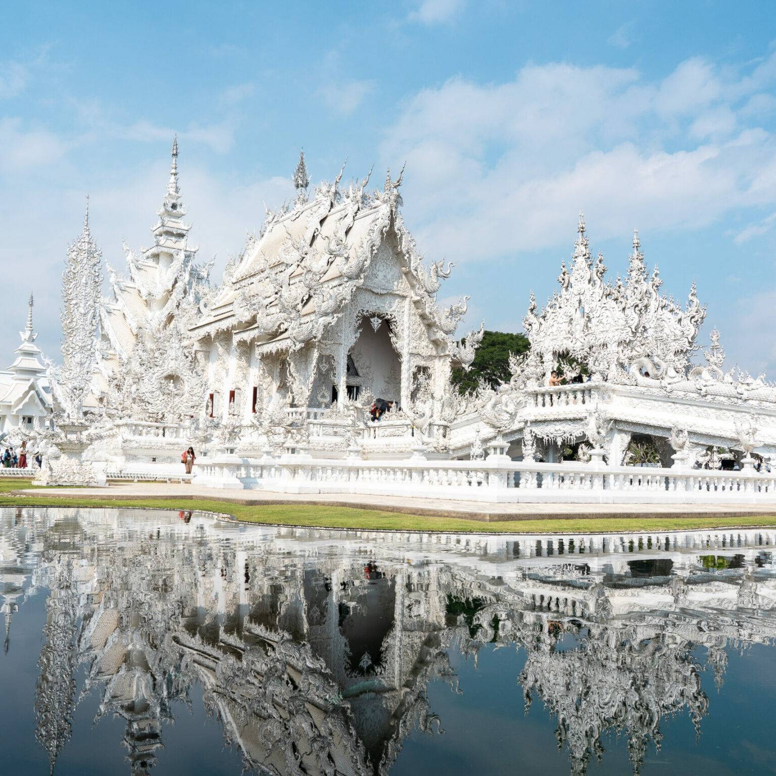 Der weiße Tempel in Chiang Rai spiegelt sich im Wasser des Sees.