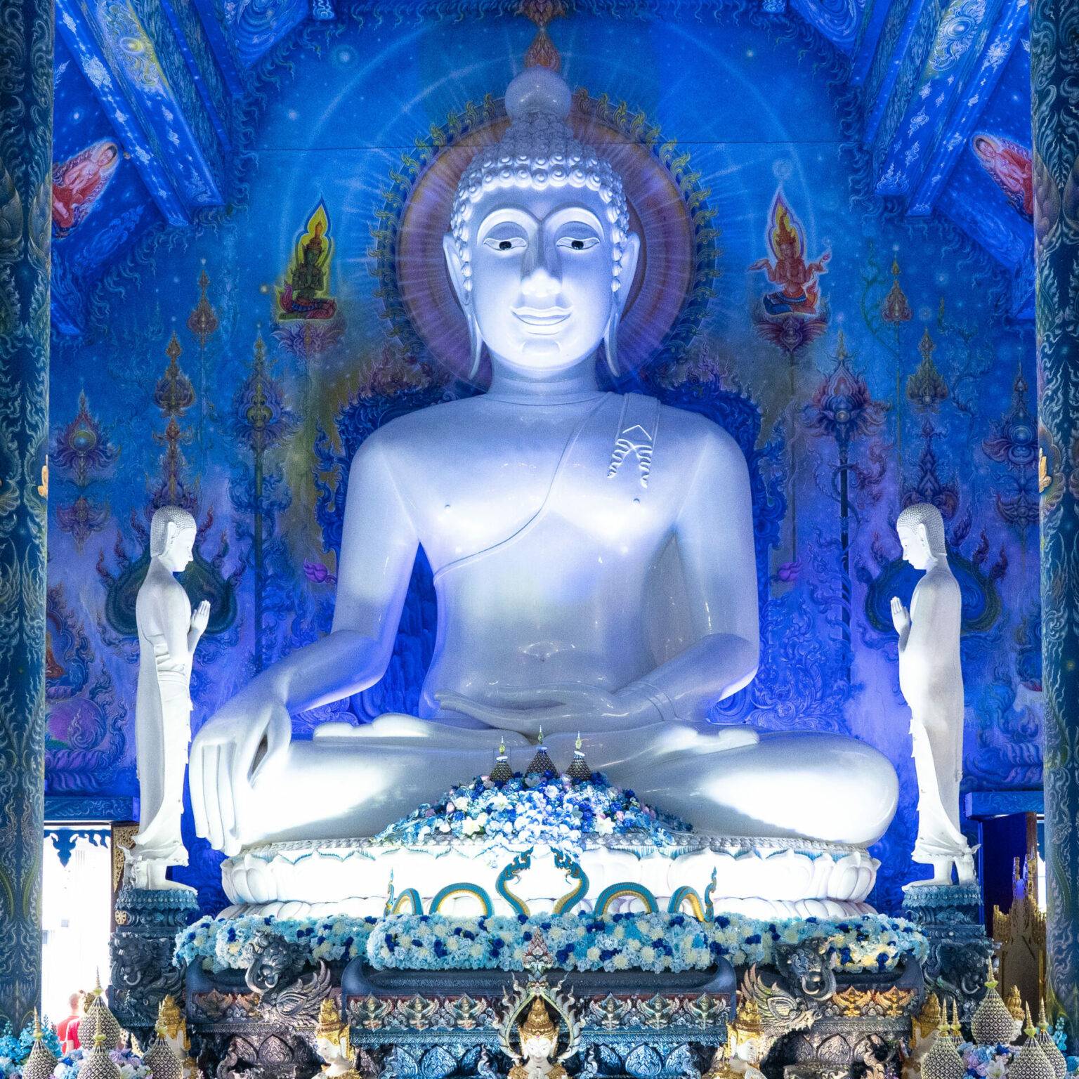 Das innere des blauen Tempels dominiert eine im Schneidersitz sitzende weiße Buddha-Statue.