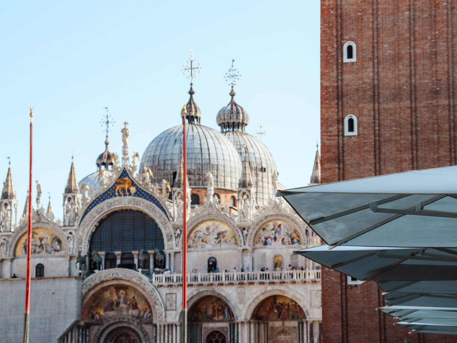 Fassade des Markusdoms in Venedig, hinter einem Café-Sonnenschirm auf dem Markusplatz.