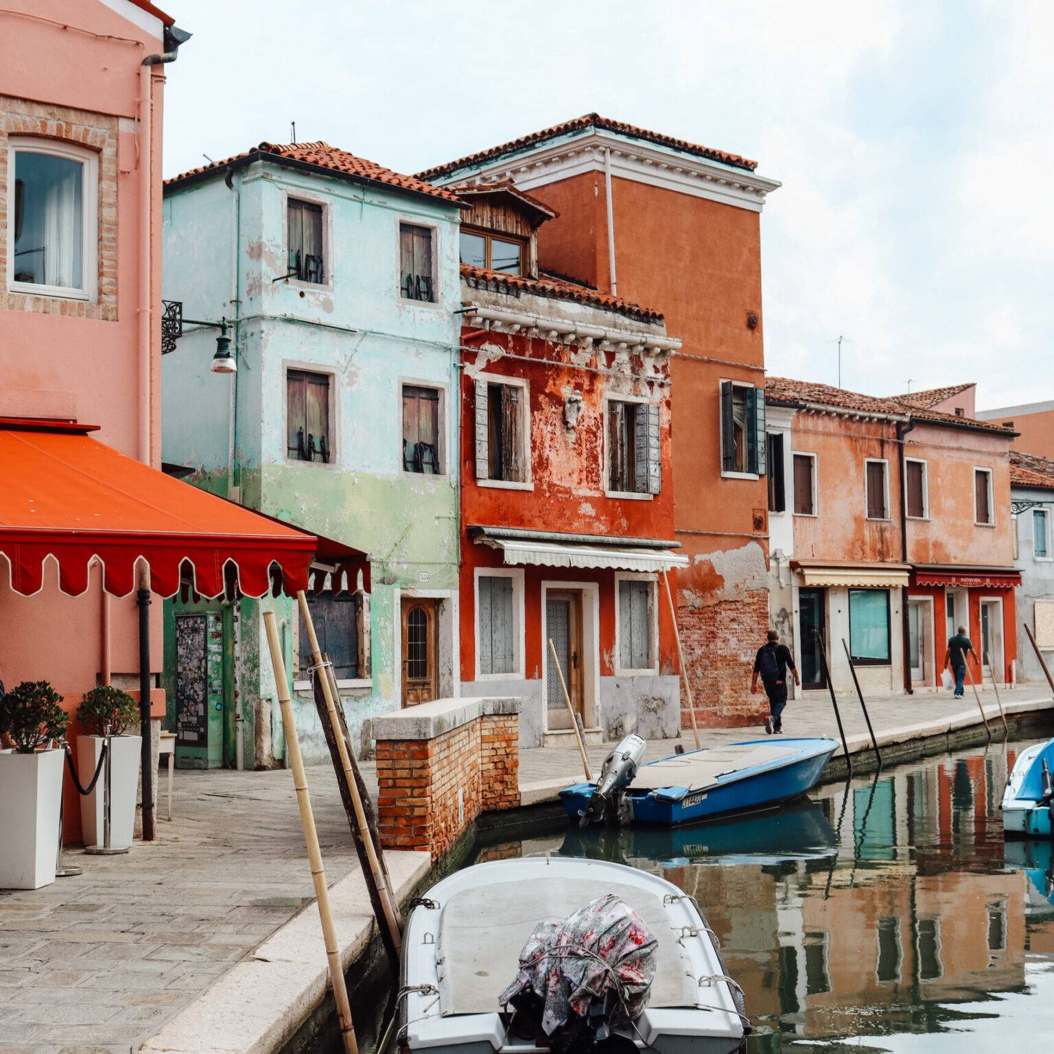 Ein Kanal auf Burano, der von bunten Häusern gesäumt ist.
