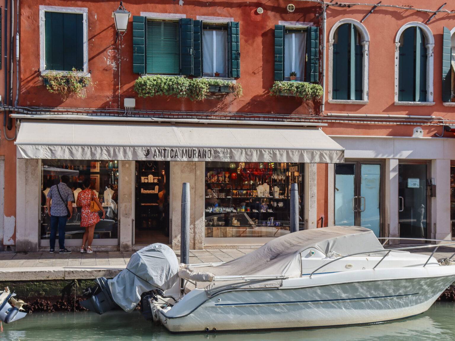 Eine Glas-Boutique am Kanal in Murano, davor ein abgedecktes Boot.