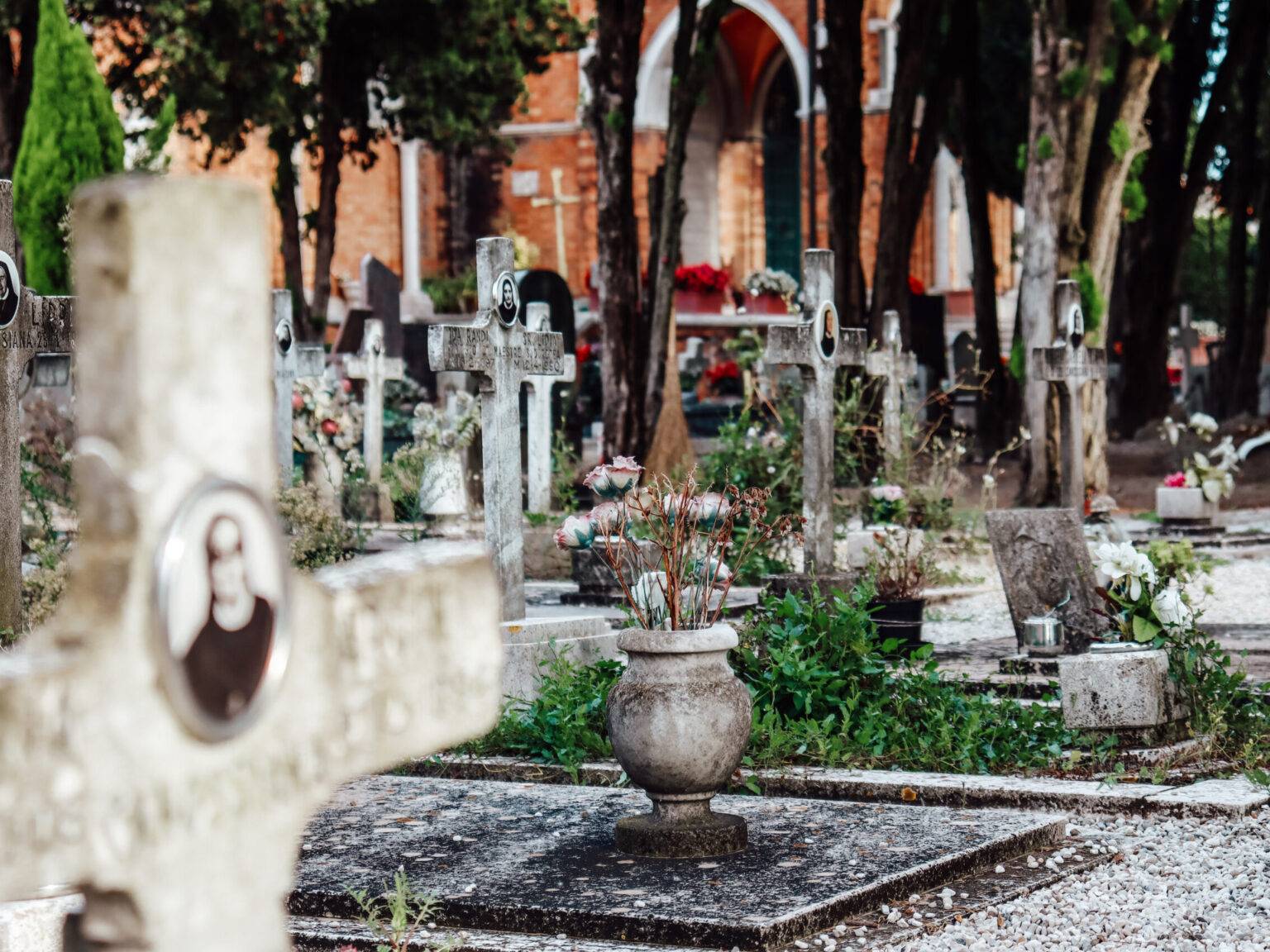 Ein steinernes Kreuz mit dem Bild einer Nonne. Im Hintergrund sind weitere Gräber.
