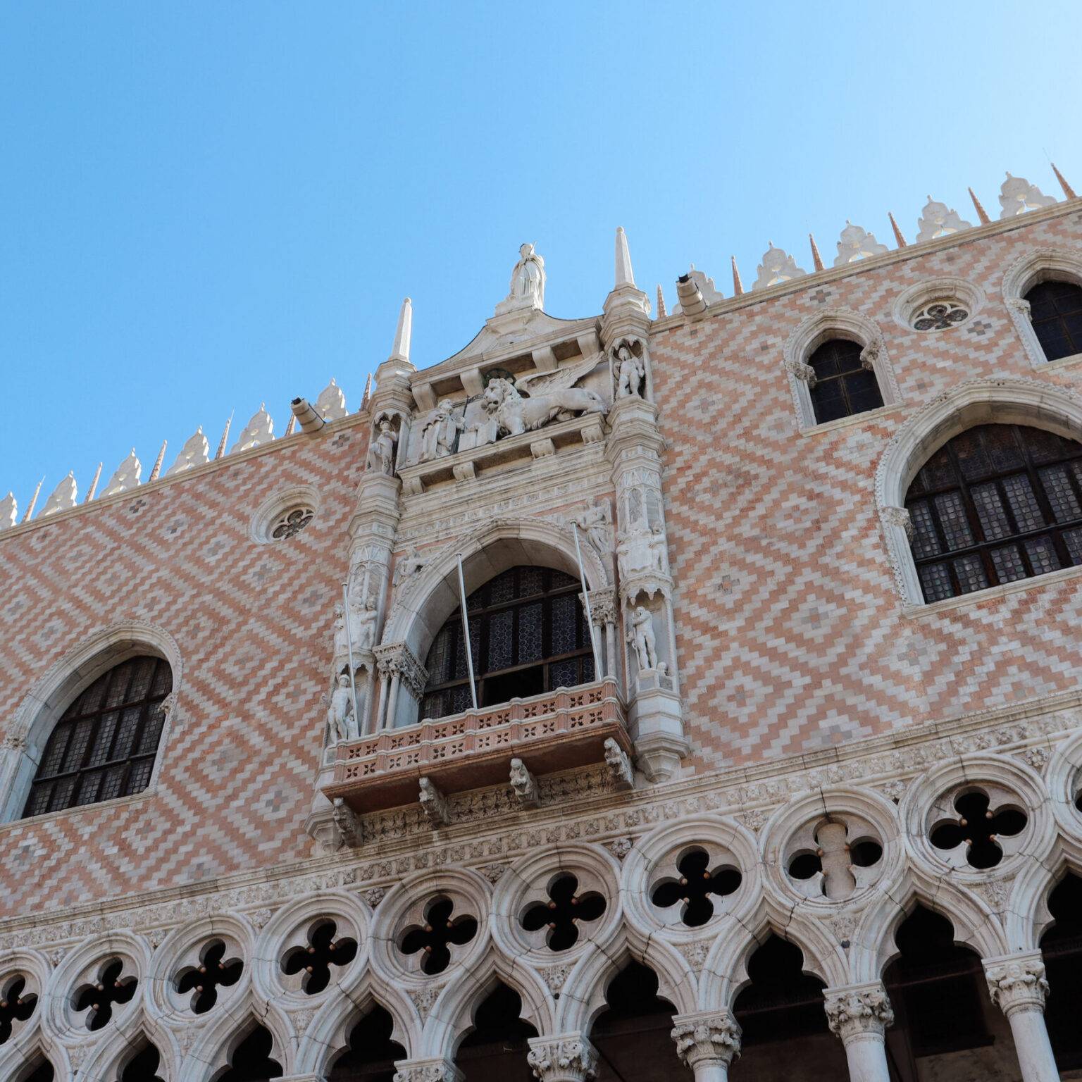 Fassade des Dogenpalasts in Venedig mit filigranen Steinornamenten und dem Markuslöwen.