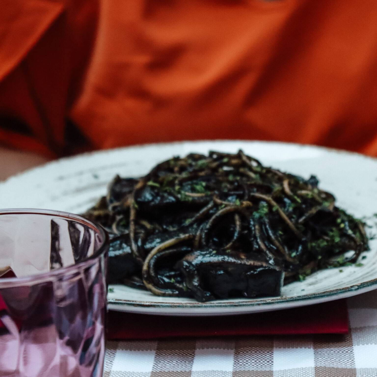 Auf einem Teller das Gericht Spaghetti al Nero di Seppia, Spaghetti in einer schwarzen Soße.