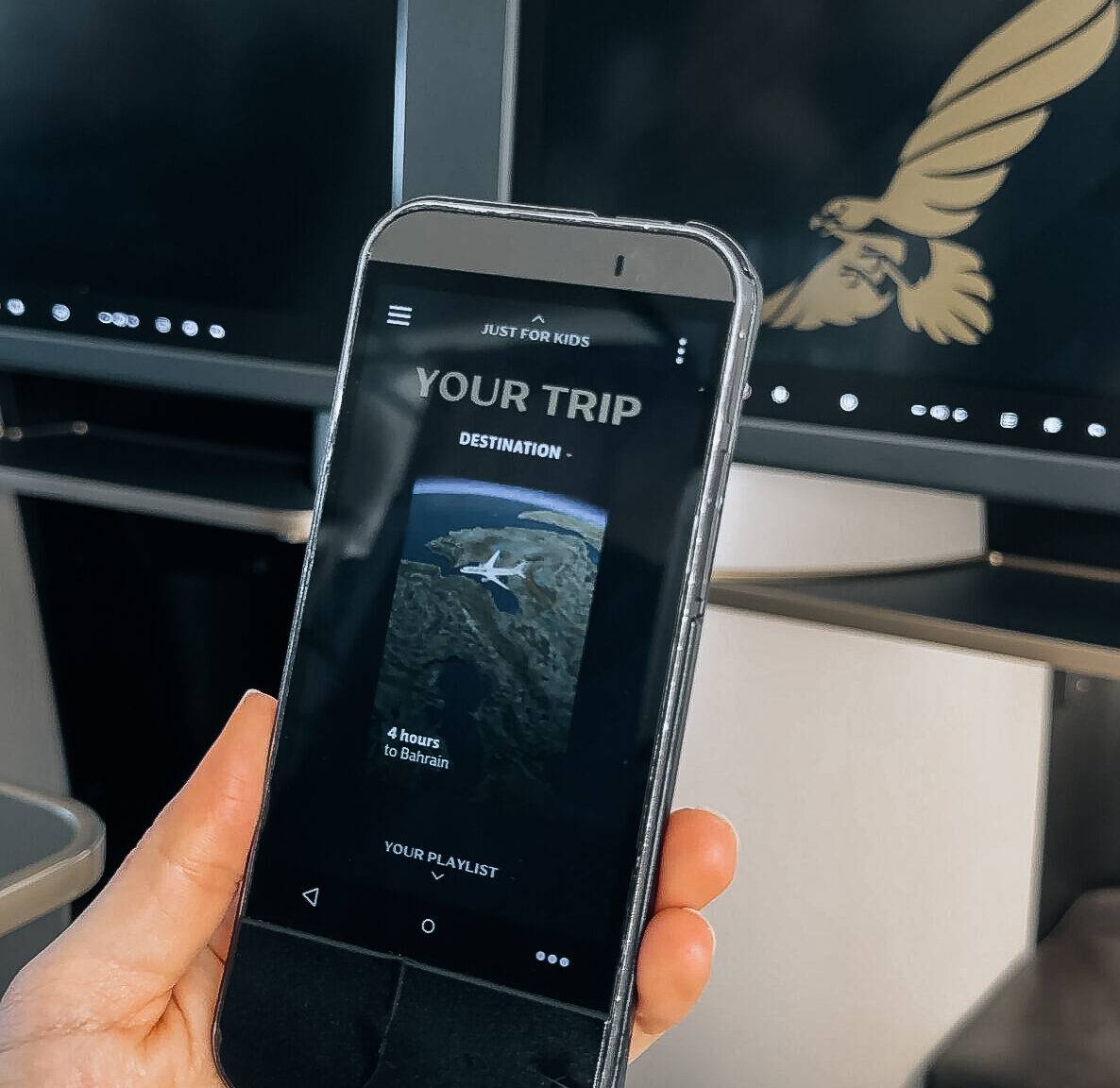 Hand hält ein Smartphone mit einer Reise-App, die eine Flugroute nach Bahrain anzeigt.