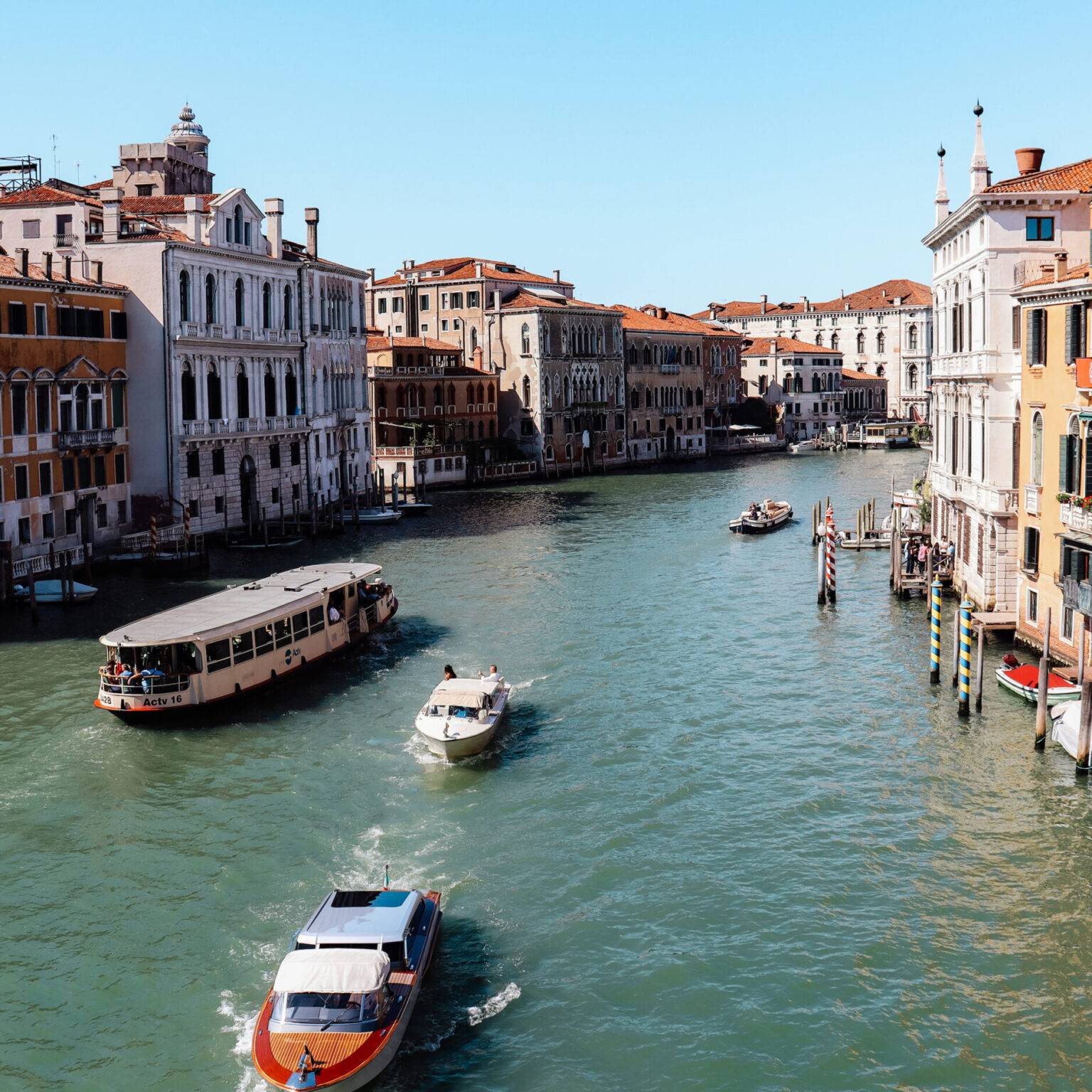 Der Blick von der Ponte dell’Accademia über den Canal Grande mit einigen Booten und eng aneinander gebauten Häusern rechts und links.