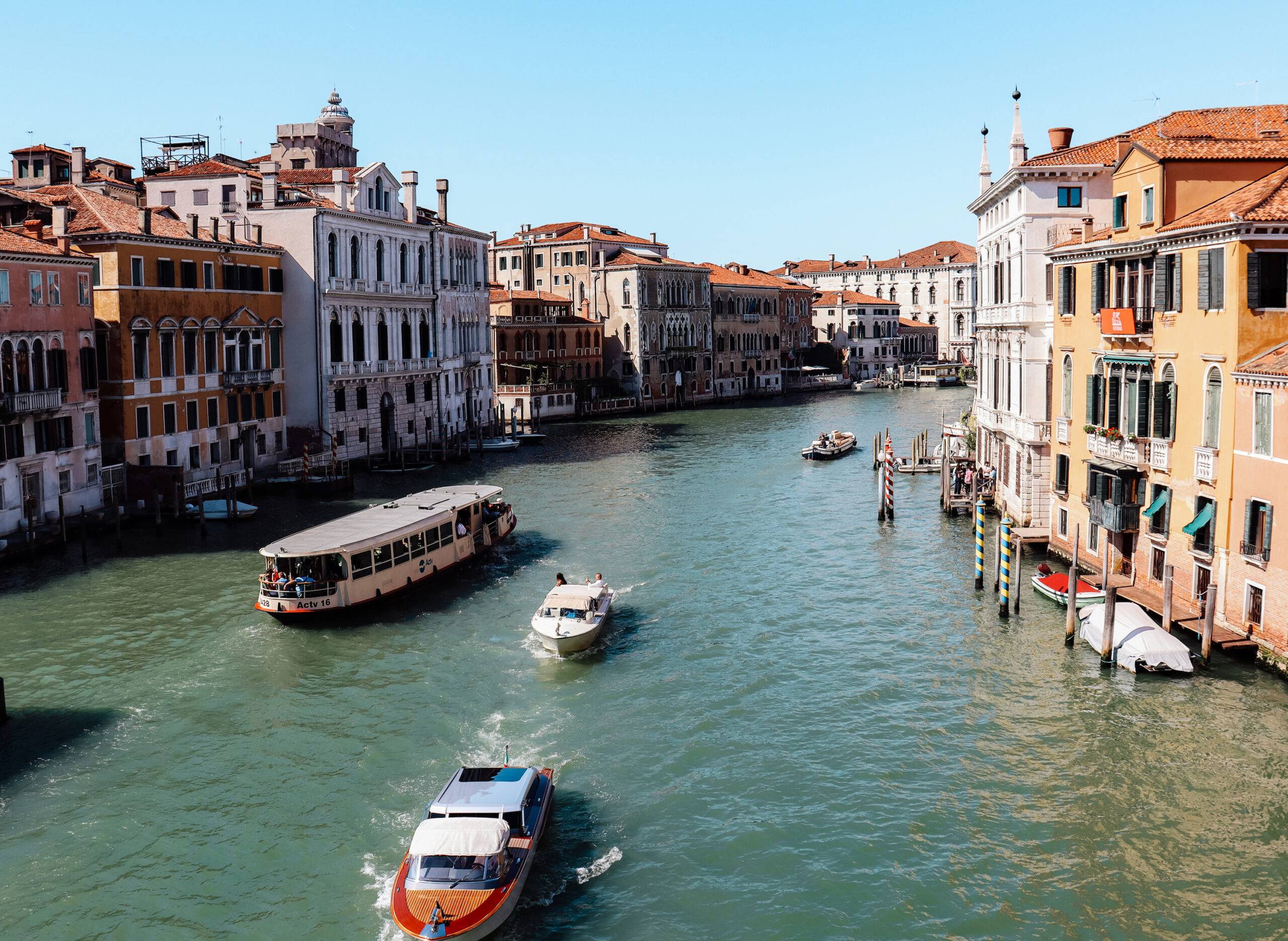 Der Blick von der Ponte dell’Accademia über den Canal Grande mit einigen Booten und eng aneinander gebauten Häusern rechts und links.
