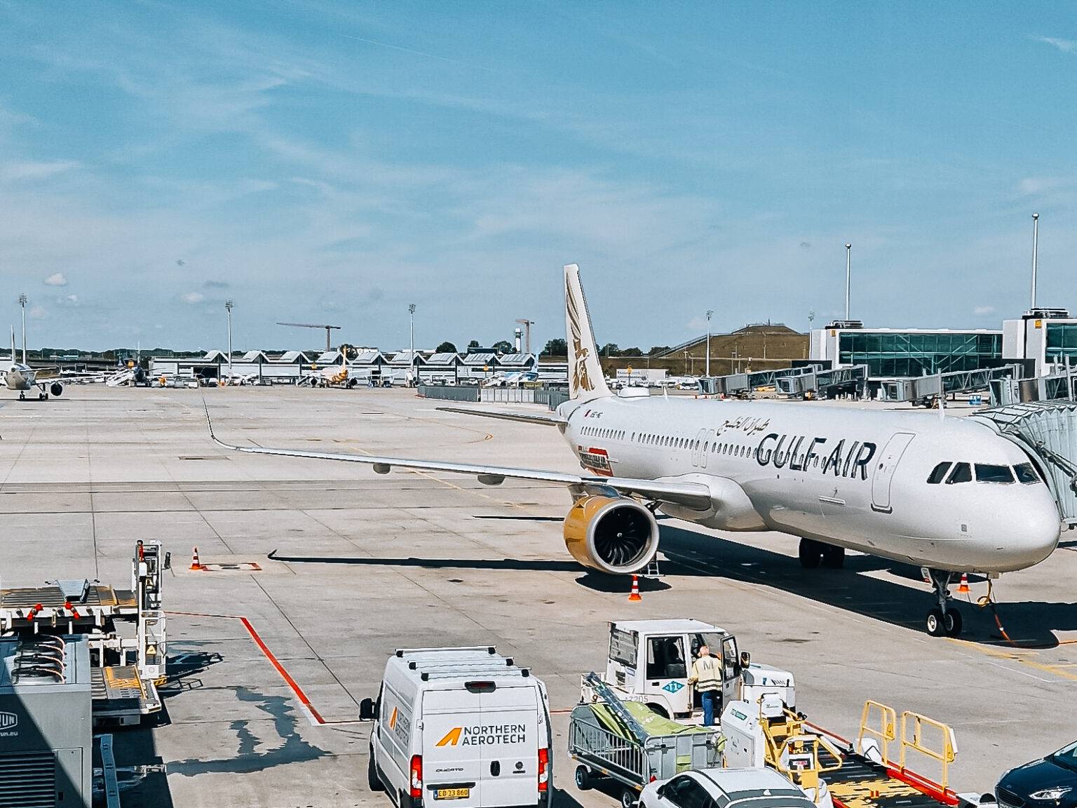 Gulf Air Flugzeug steht am Flughafen auf dem Vorfeld mit Treppengerät und Gepäckwagen in der Nähe.