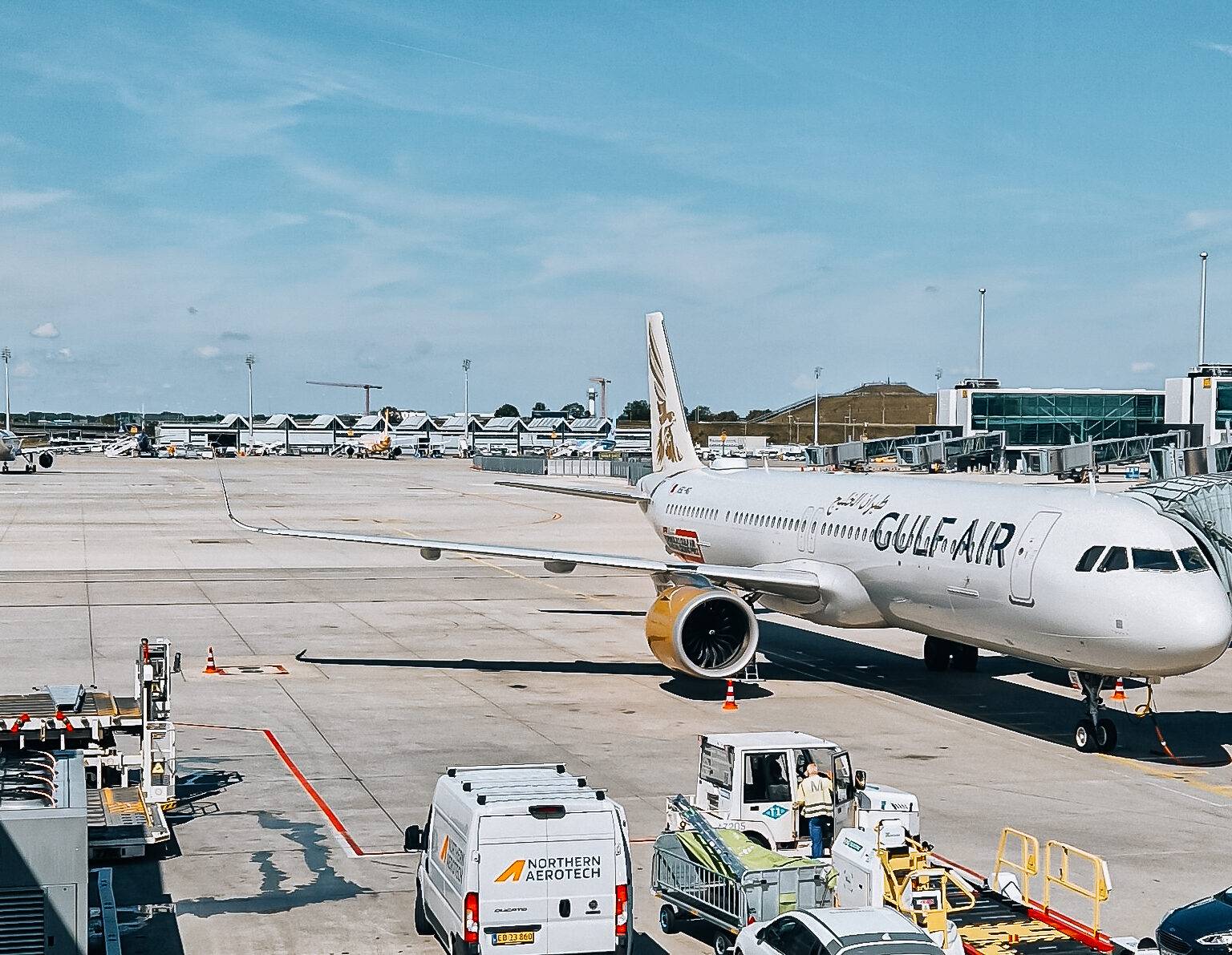 Gulf Air Flugzeug steht am Flughafen auf dem Vorfeld mit Treppengerät und Gepäckwagen in der Nähe.