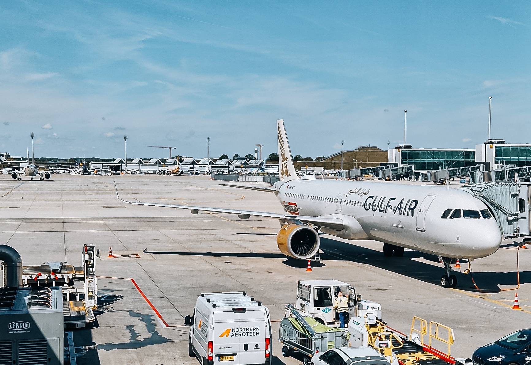 Gulf Air Flugzeug steht am Flughafen auf dem Vorfeld mit Treppengerät und Gepäckwagen in der Nähe.