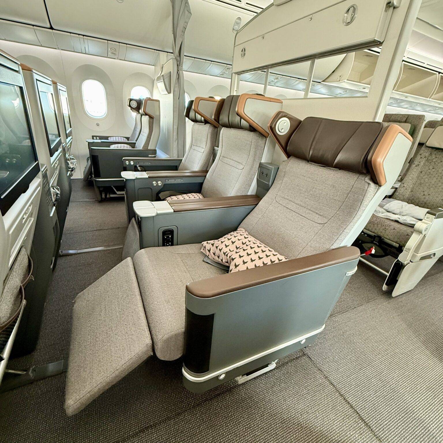 Bequeme Flugzeugsitze in einer modernen Kabine, mit gepolsterten Armlehnen und einem Fensterplatz im Hintergrund.