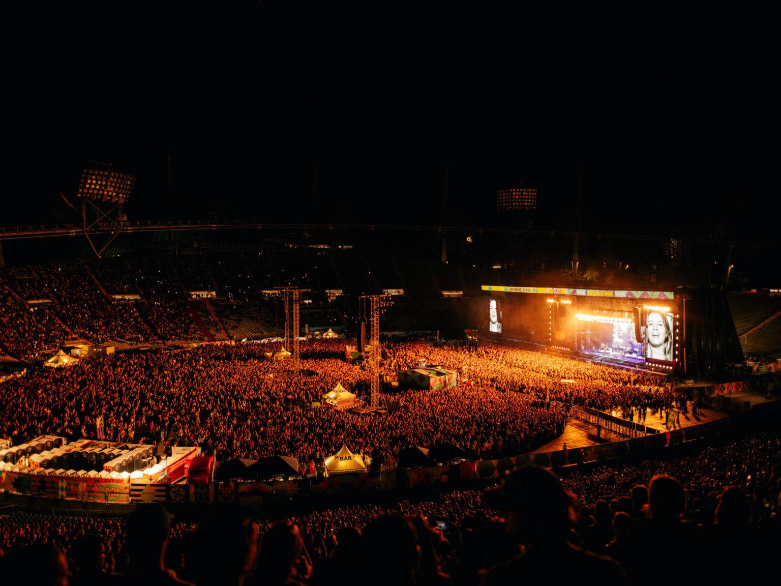 Der volle Olympiapark bei Nacht, beleuchtet von Bühnenlichtern, während des Superbloom Festivals.