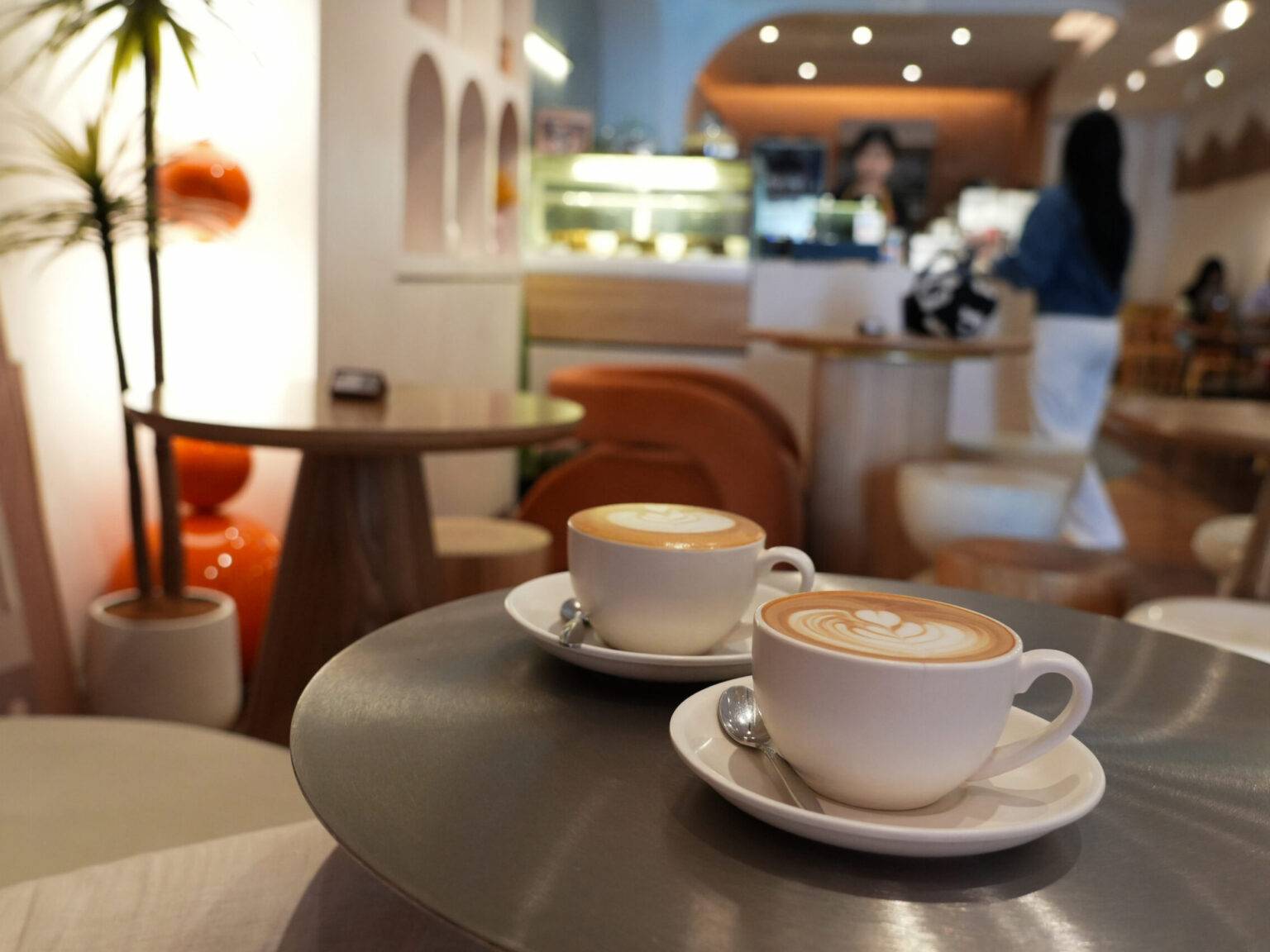 Zwei Tassen Kaffee auf einem Tisch in einem modernen Café mit einer hellen, einladenden Atmosphäre.