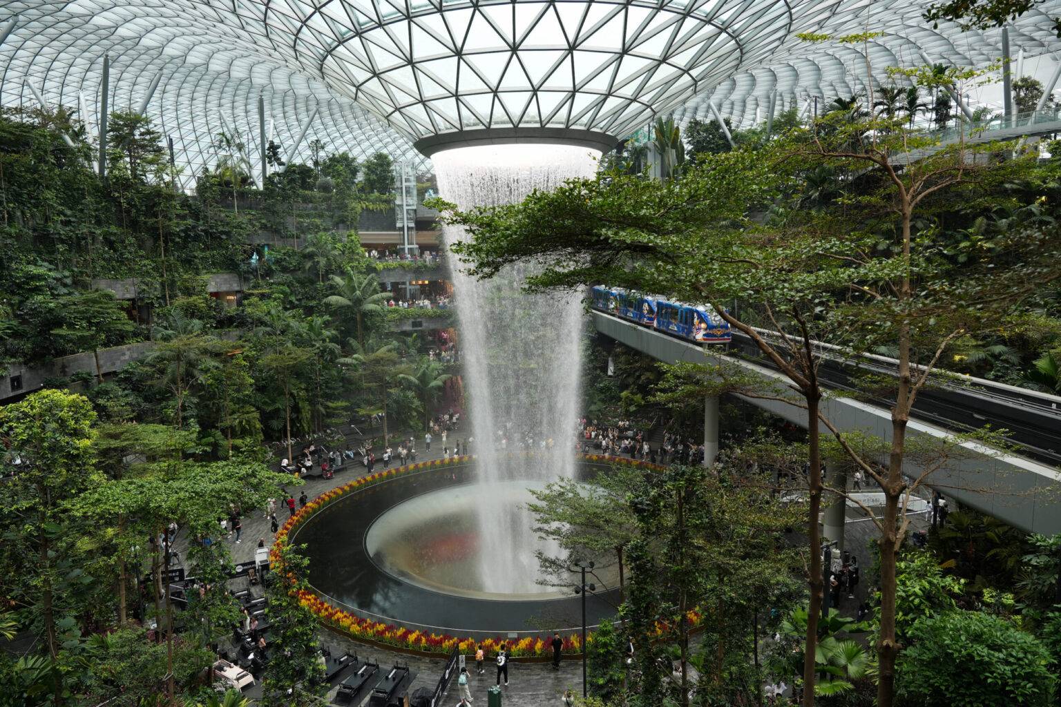 Der Indoor-Wasserfall im Jewel Changi Airport in Singapur, umgeben von einem grünen Regenwald-Innenhof