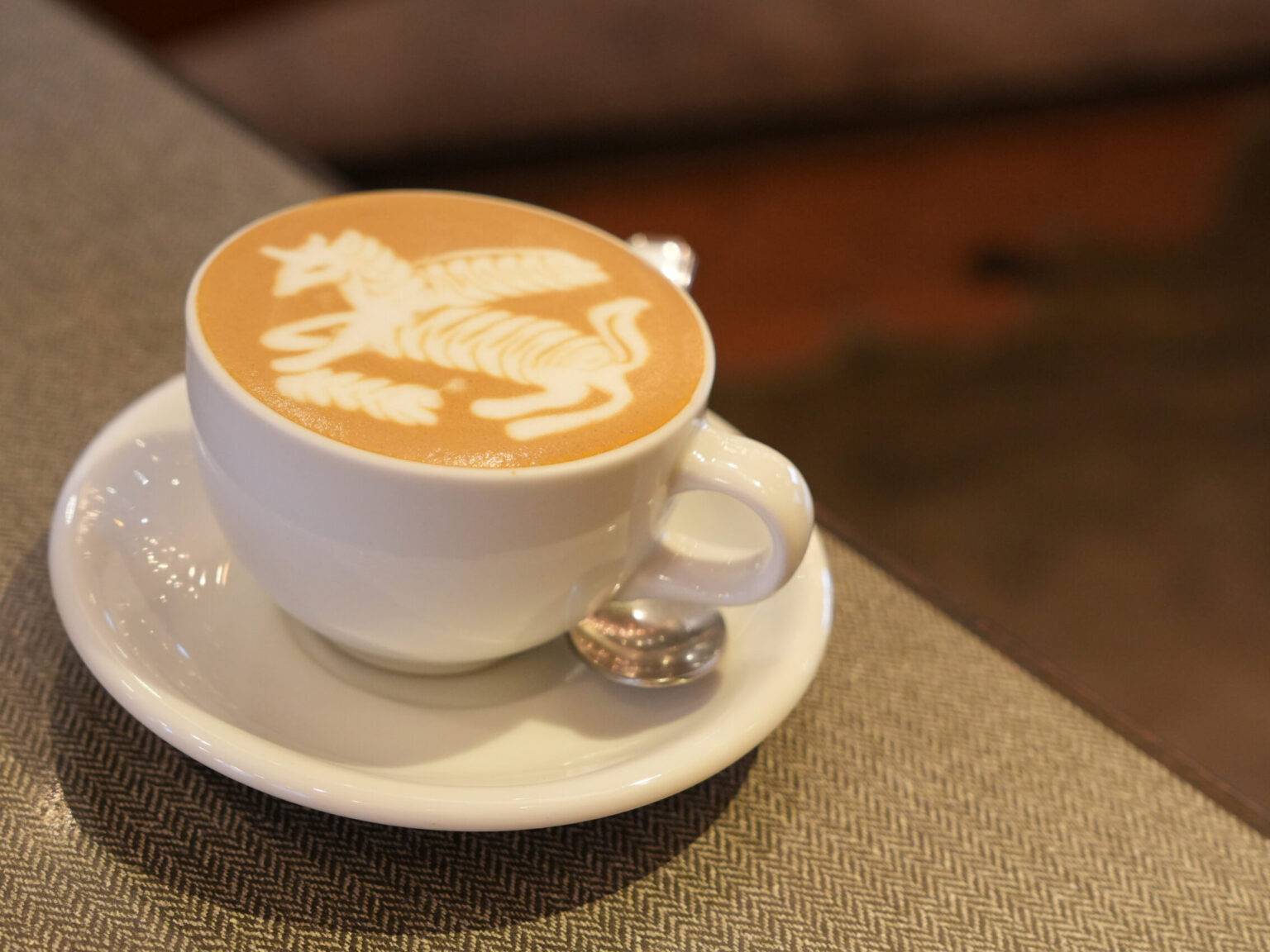 Tasse Kaffee mit kunstvoller Latte-Art die ein Pegasus zeigt.