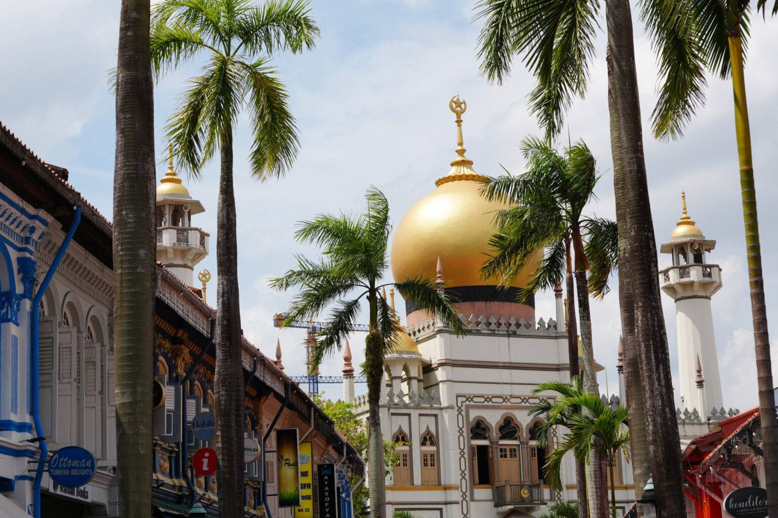 Straße mit Palmen und Blick auf die Sultan Mosque in Singapur.