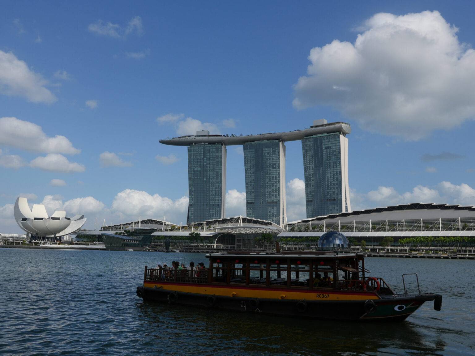 Touristisches Boot fährt am futuristischen Marina Bay Sands Hotel in Singapur vorbei