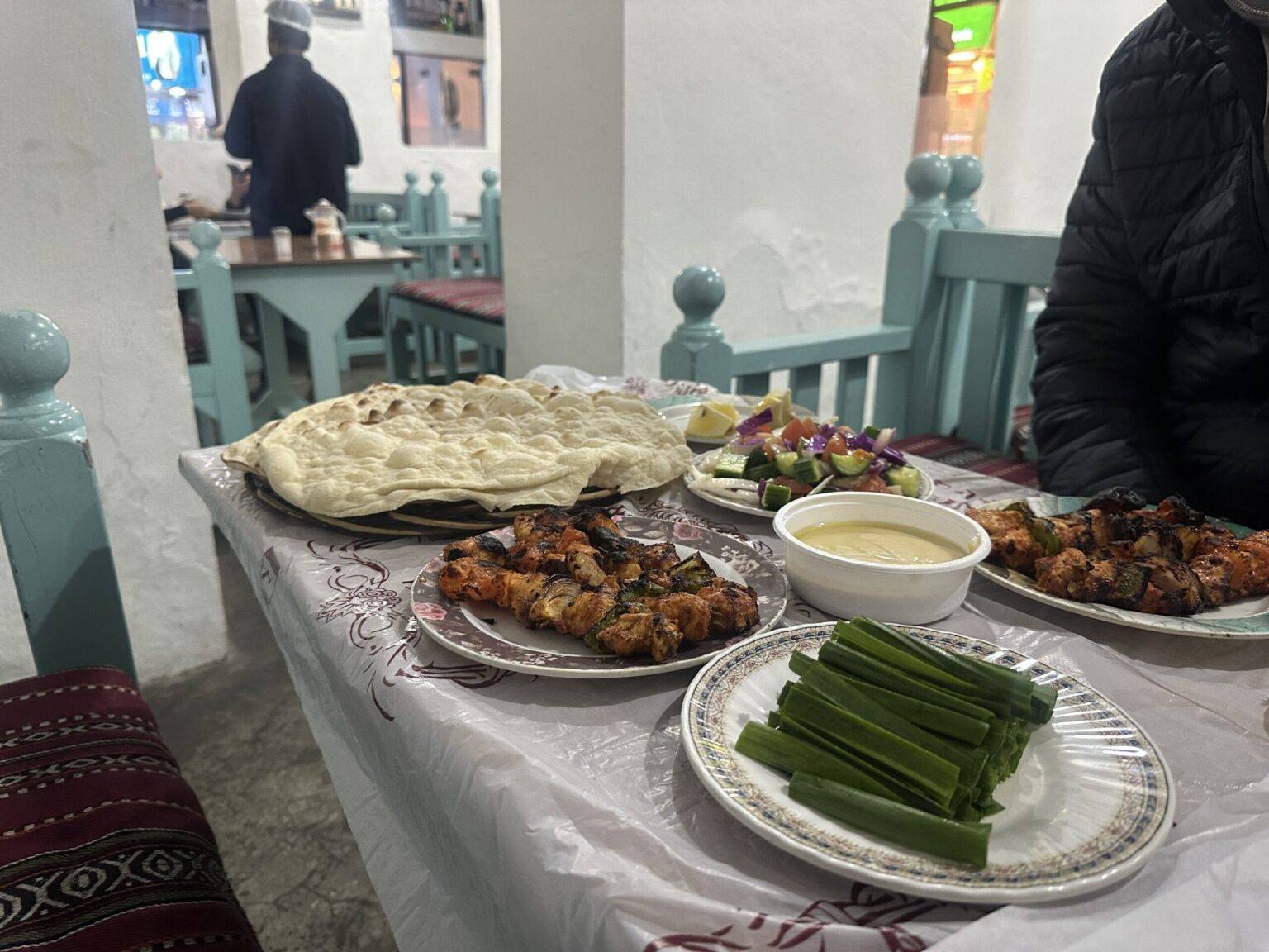 Teller mit gegrilltem Fleisch, Gemüse, Brot und Dips auf einem Tisch in einem Restaurant.