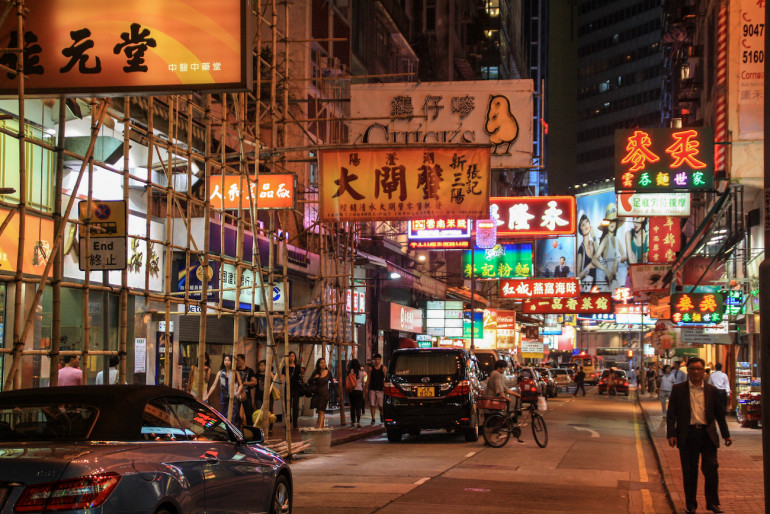 Viele bunte Leuchtschilder zieren die Häuserfassaden von Hongkongs Straße Nathan Road bei Nacht.