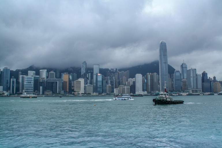 Von der Uferpromenade des Stadtteils Tsim Sha Tsui reicht der Blick bis zur wolkenverhangenen Skyline Hongkongs, China.